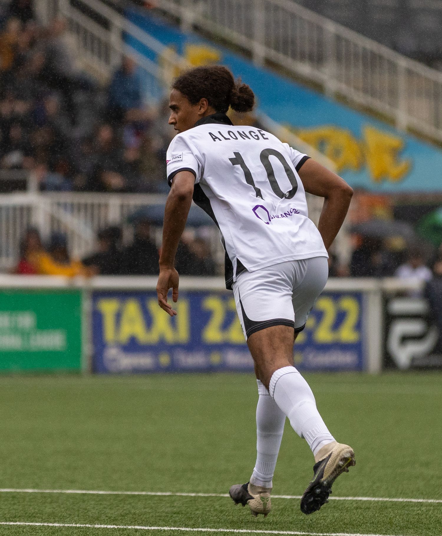 Soccer player wearing number 10 Alonge jersey in white uniform running on field during a match.