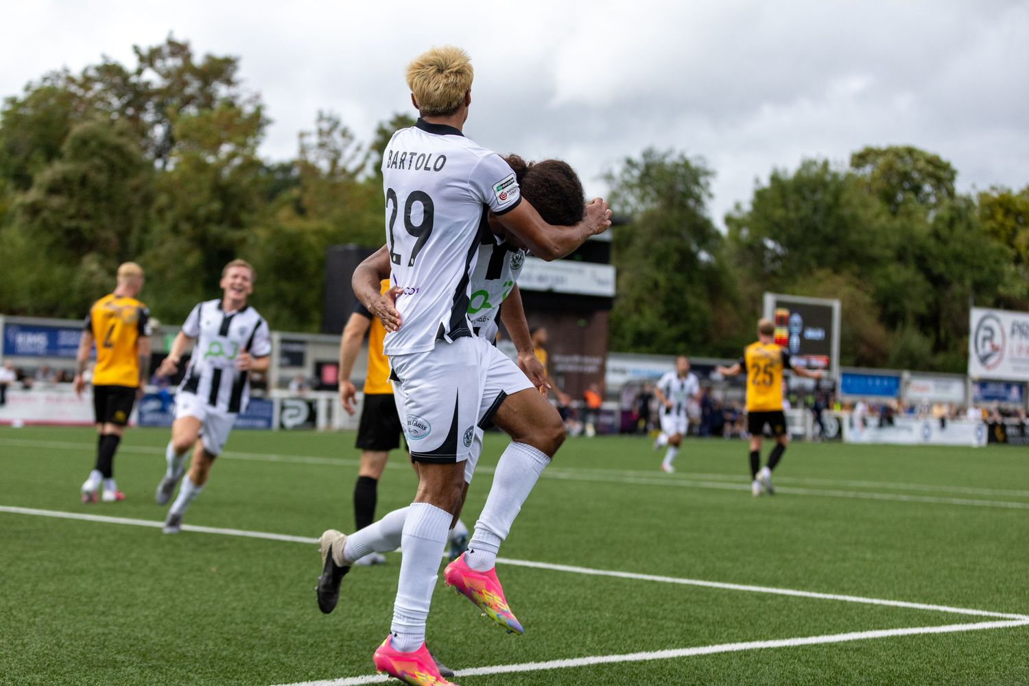 Soccer player wearing number 19 jersey celebrates a goal with teammate during a match on a green field.