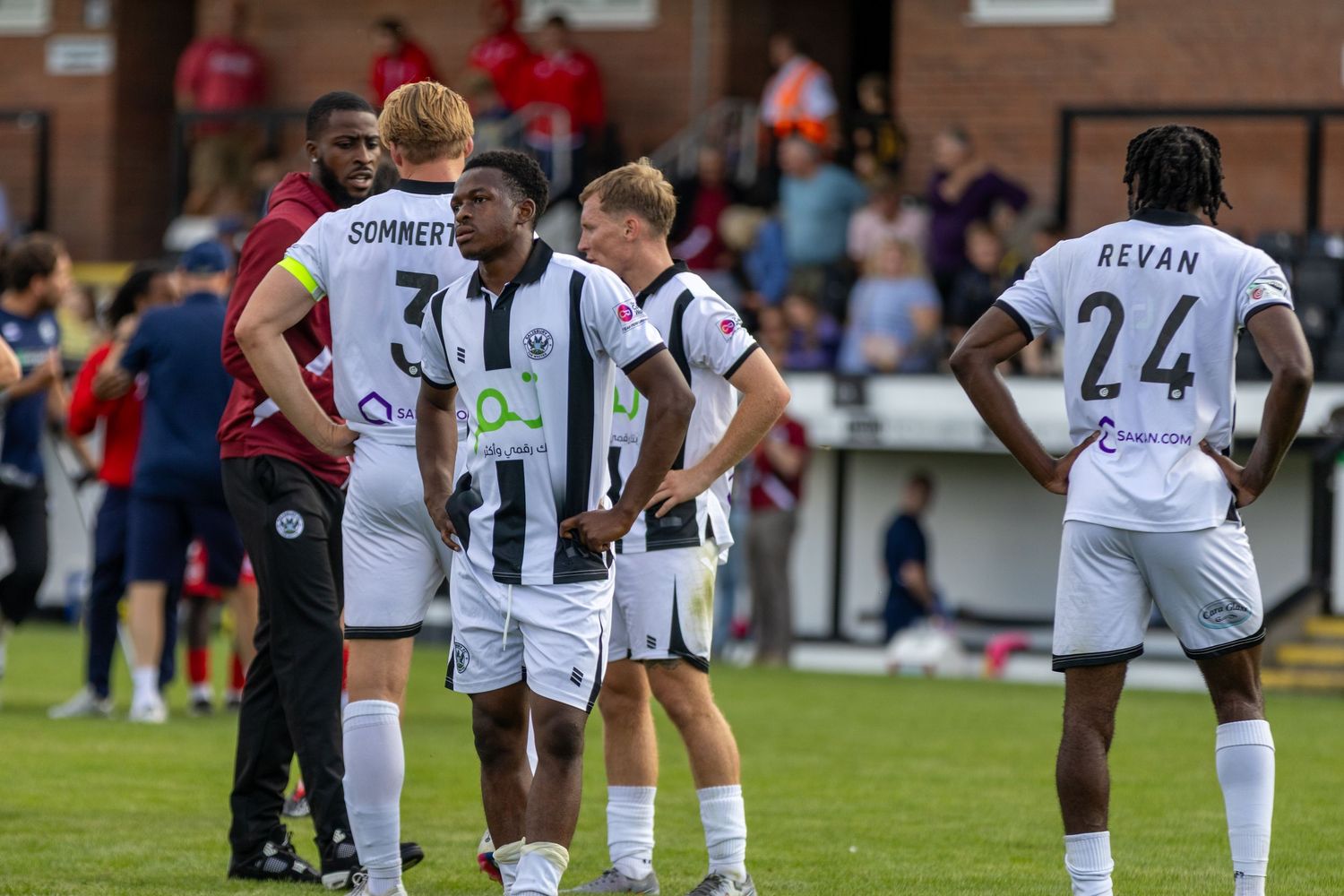 Soccer players in black and white uniforms huddle on the field during a match, with player numbers 31 and 24 visible.