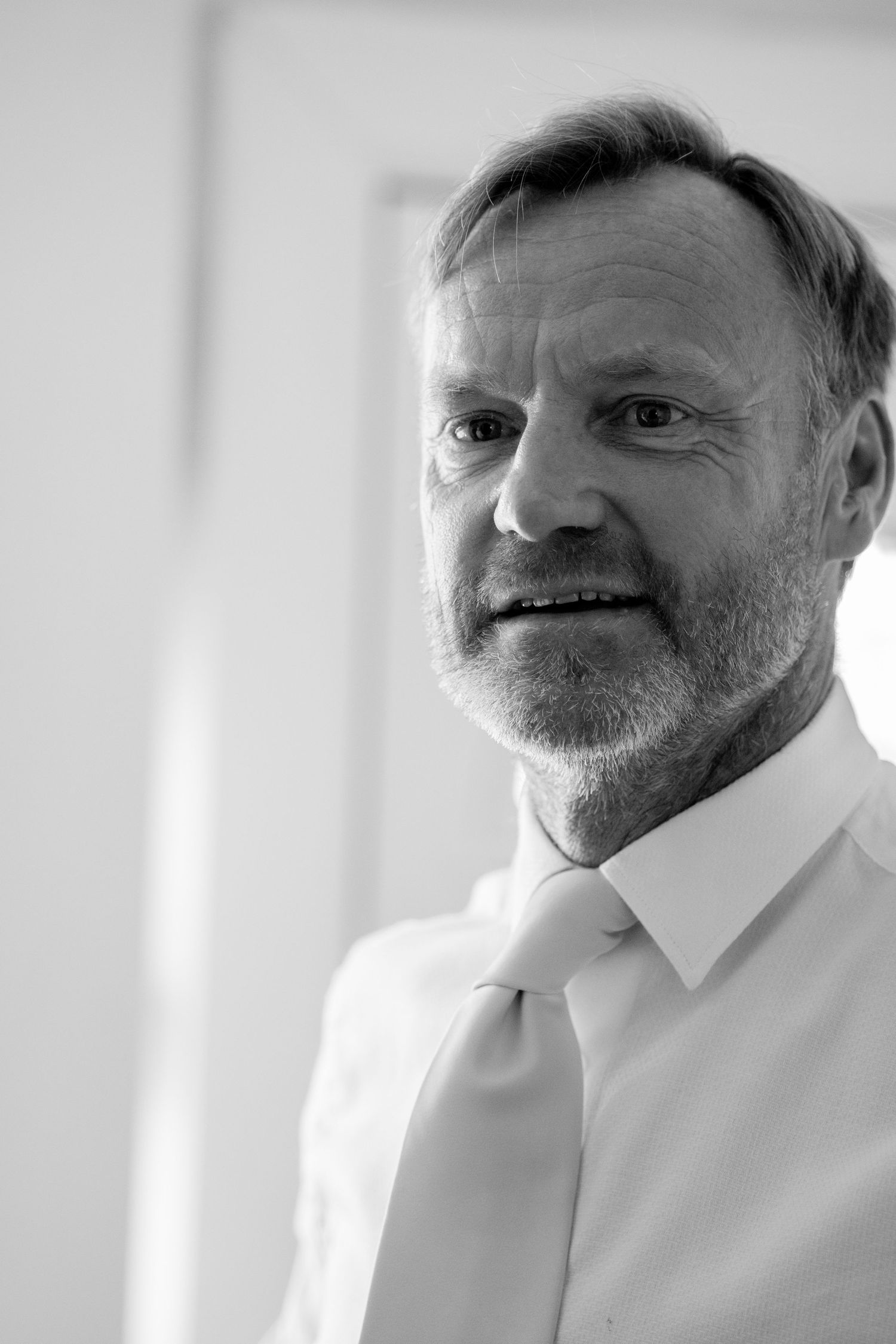 Black and white portrait of distinguished older man with beard wearing white dress shirt and tie.