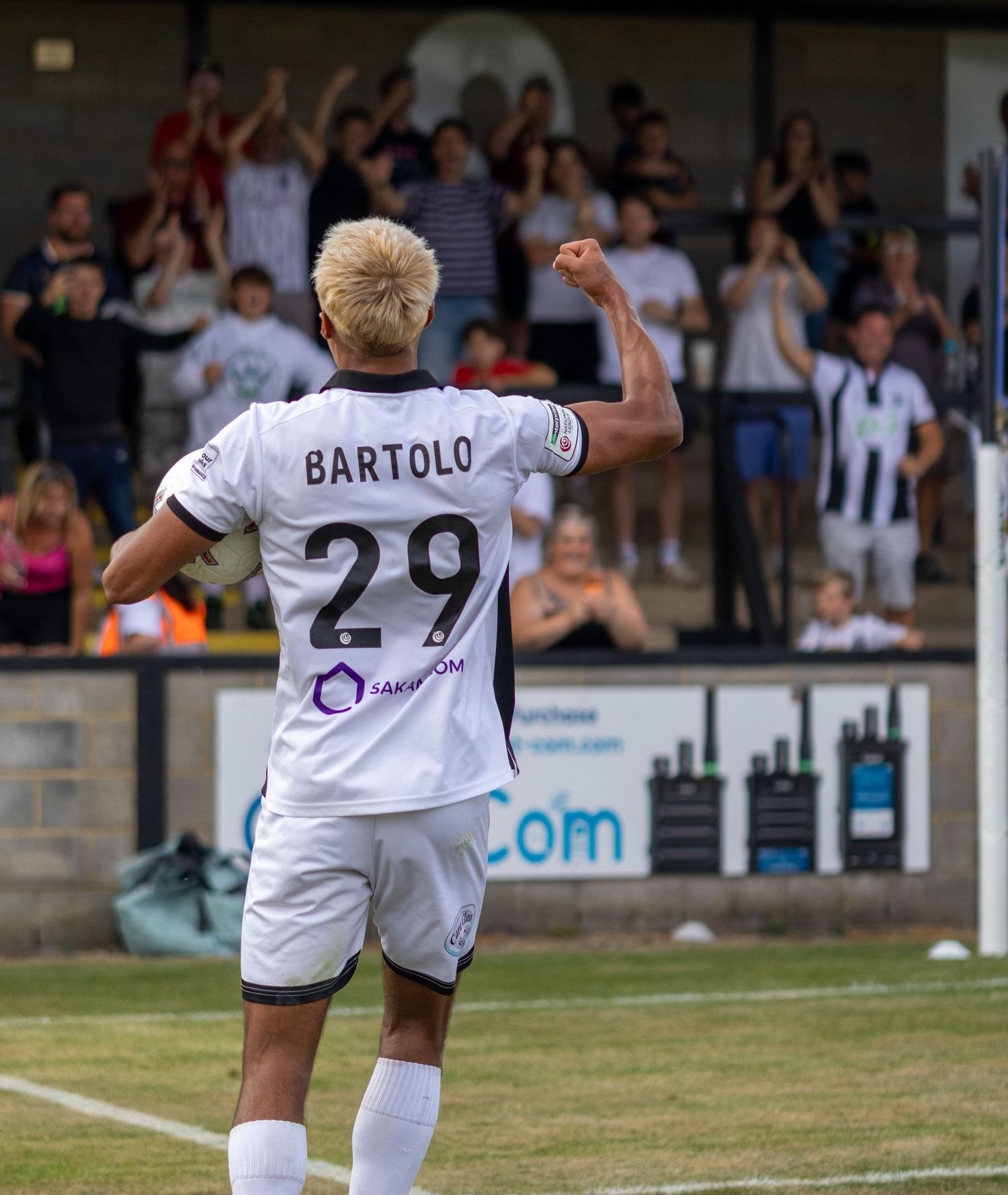Bartolo number 29 in white football kit celebrates with raised fist before applauding fans.