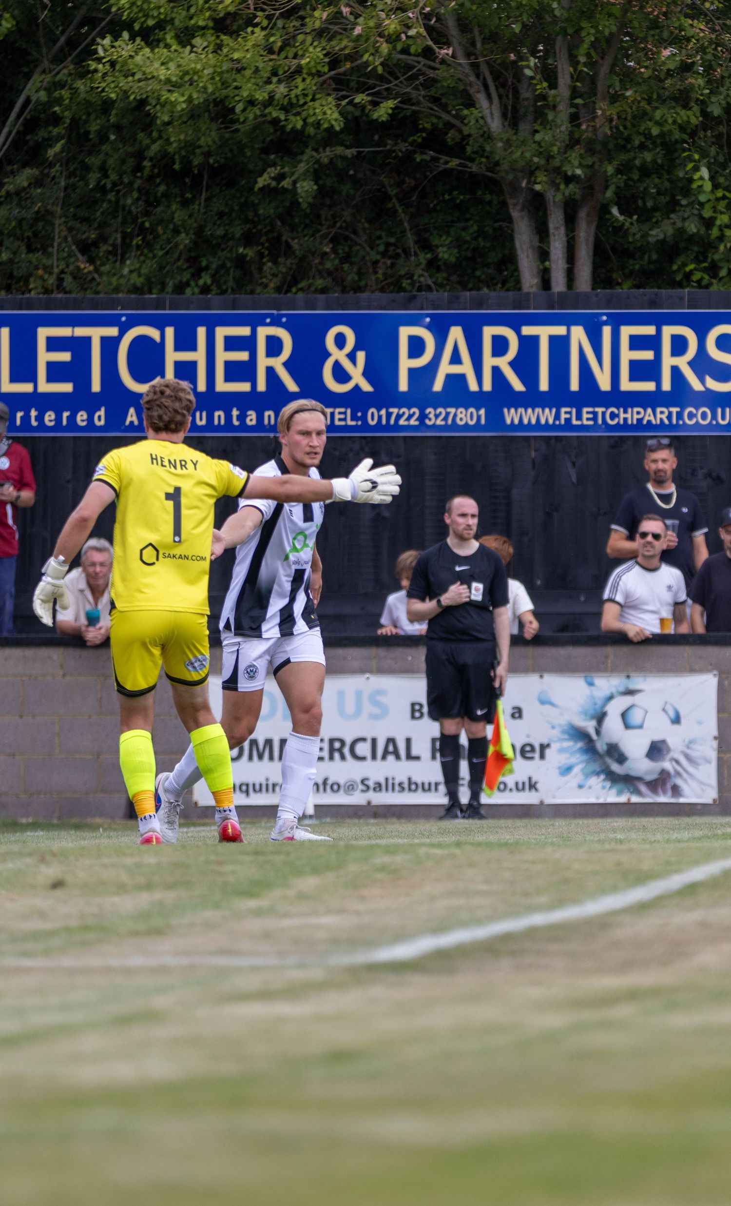 A goalkeeper wearing number 1 Henry jersey receives instructions from a teammate during a match.