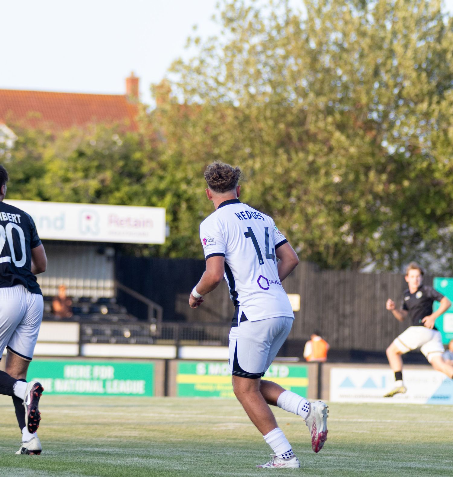Football player Hedges number 14 in white kit running on pitch during daytime match.