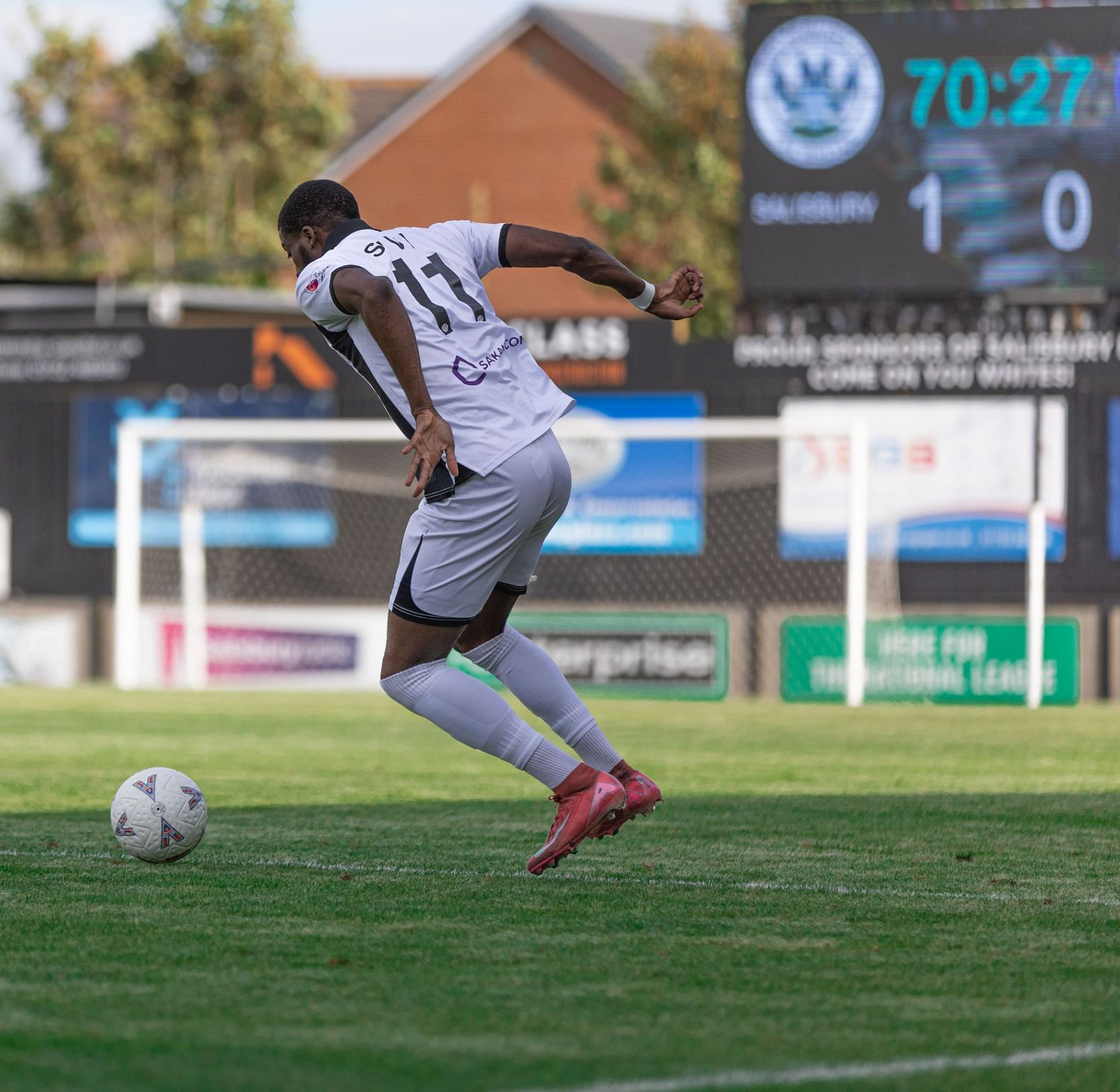 Soccer player number 11 in white kit kicks ball during match with scoreboard showing 1-0 at 70:27.