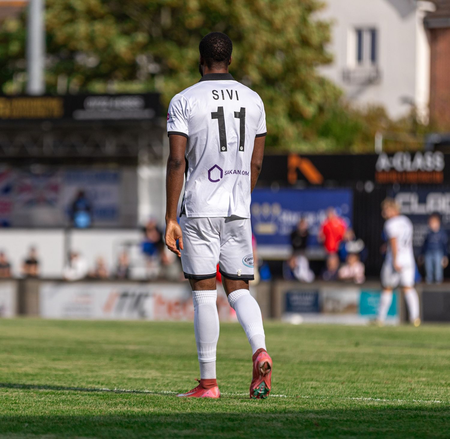 Soccer player wearing white jersey number 11 with name SIVI on back, standing on green grass field during match.