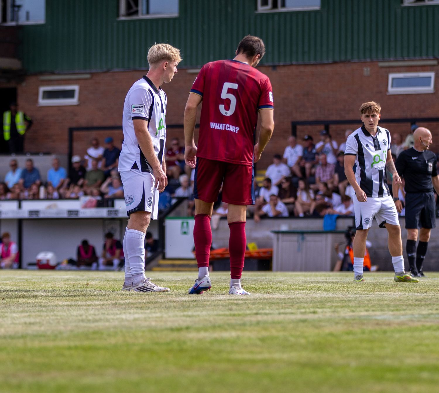 Two soccer players, one wearing number 5 in maroon, stand face to face during a match stoppage.