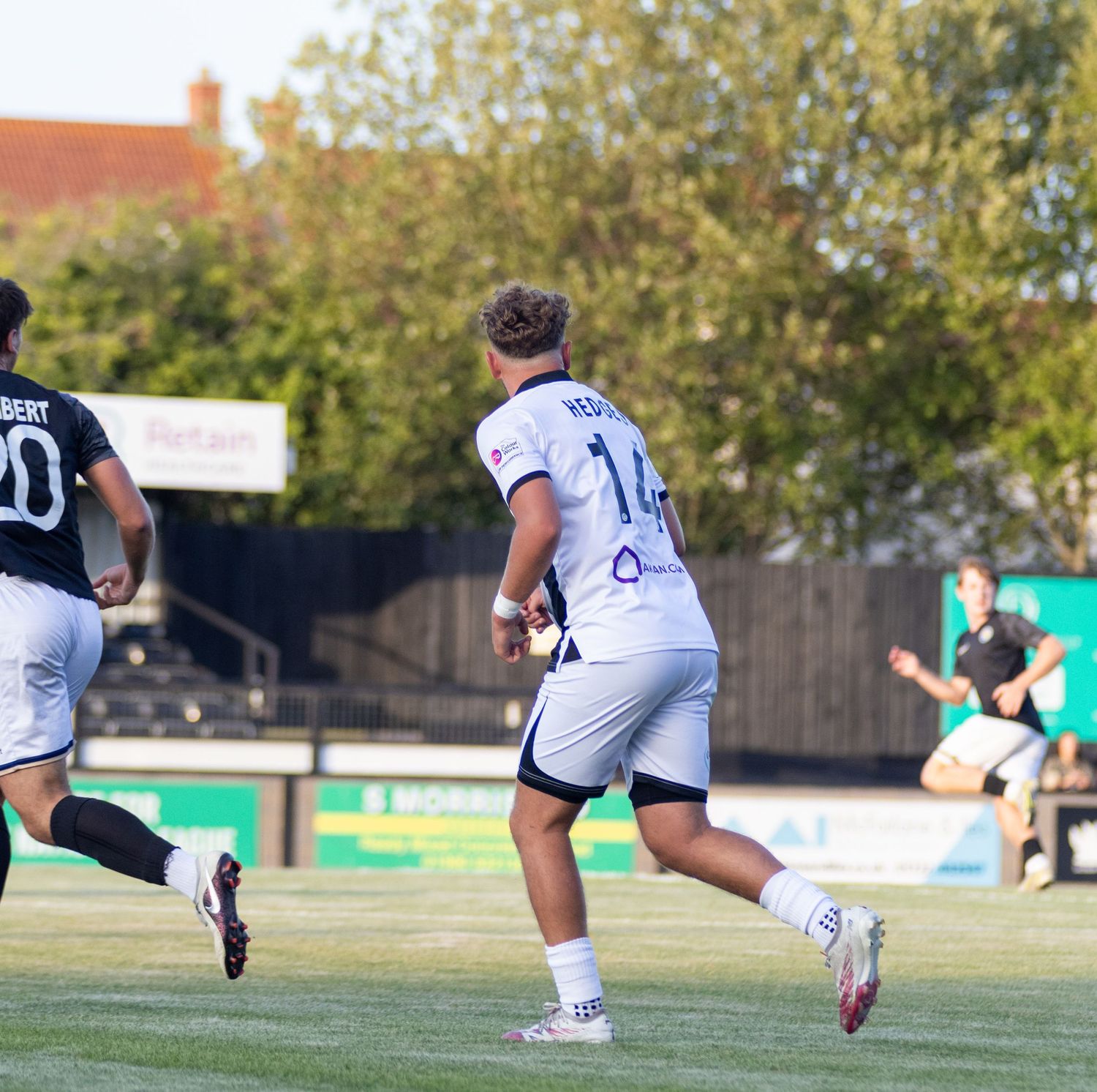 Player number 14 Hedges in white away kit running during sunny outdoor football match.
