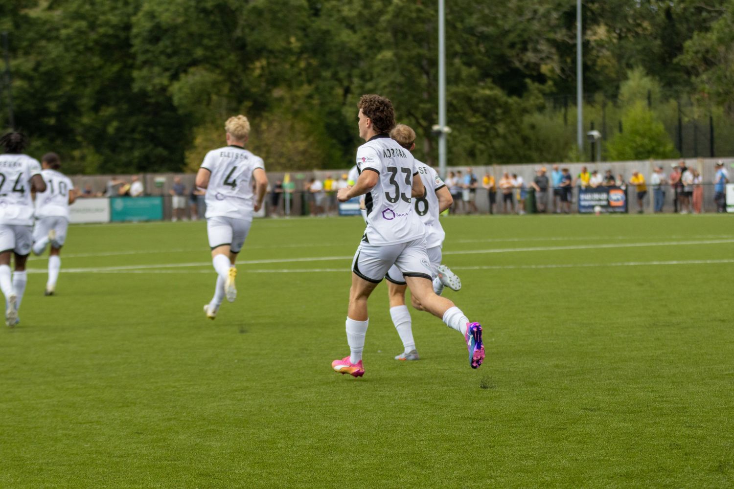 A footballer wearing number 33 in a white kit runs across the pitch during a non-league football match.