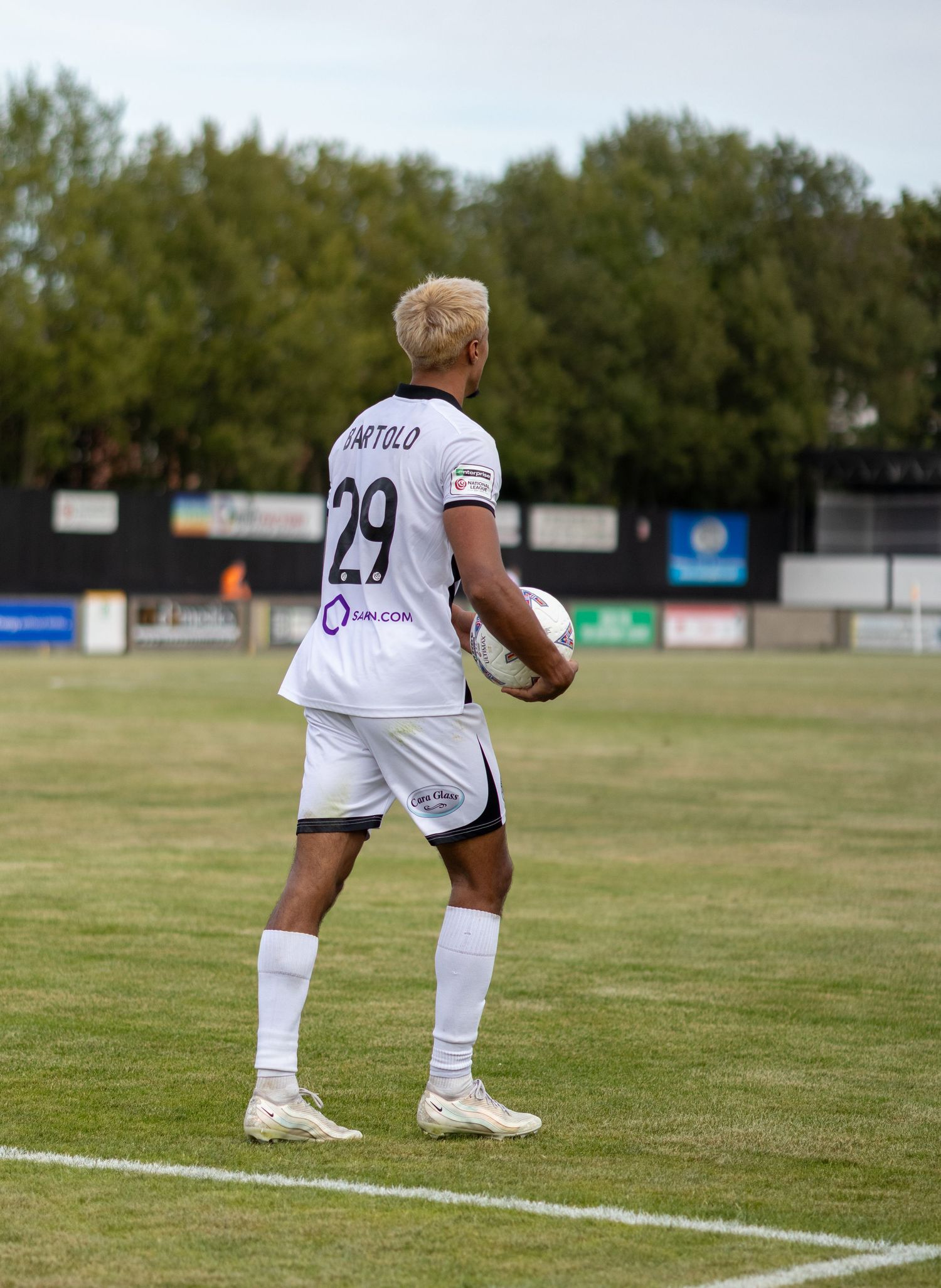 Footballer BARTOLO number 29 holds ball in white kit preparing for a throw-in during a match.
