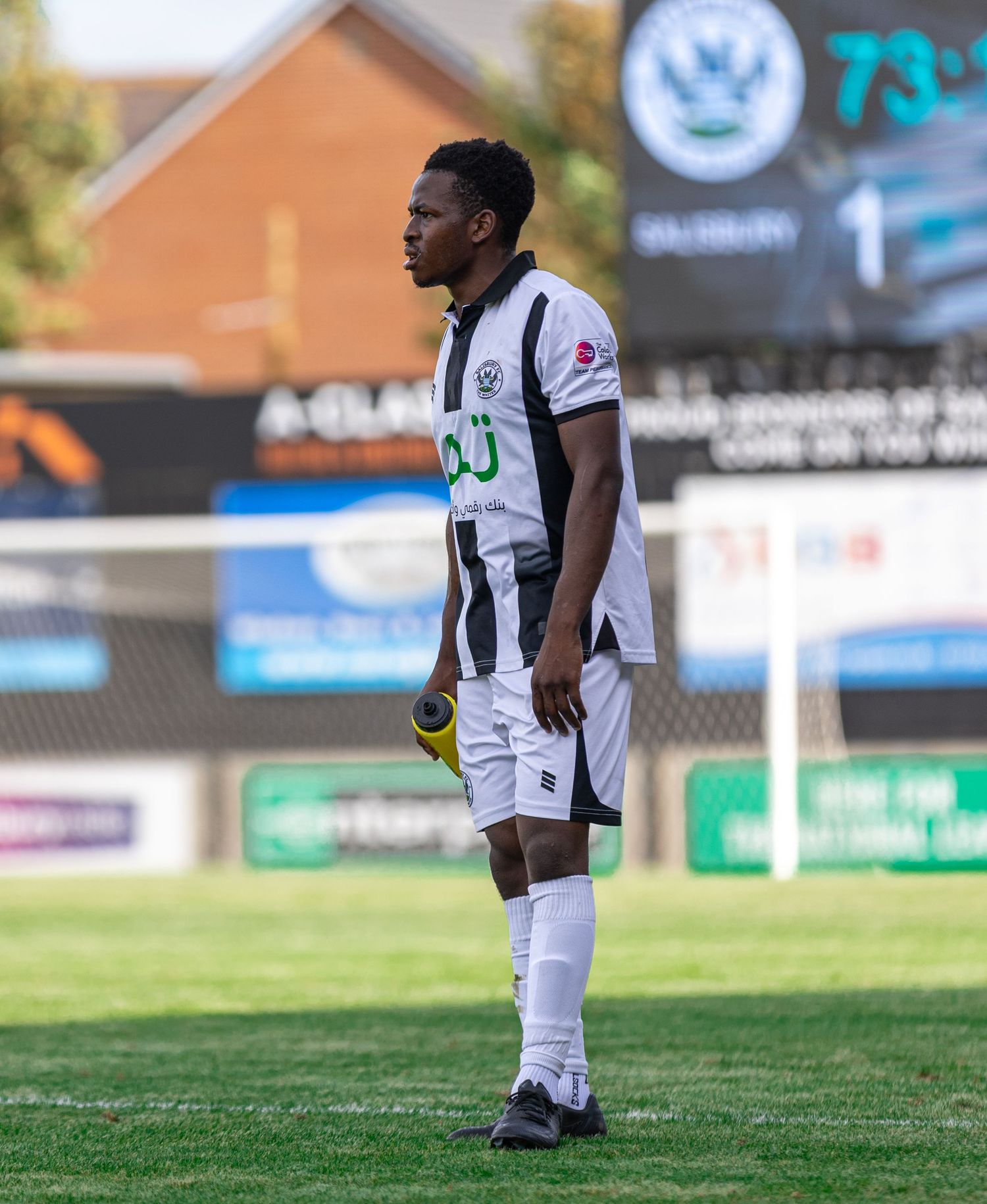 A soccer player in black and white uniform stands on the field during a match at the 73rd minute.