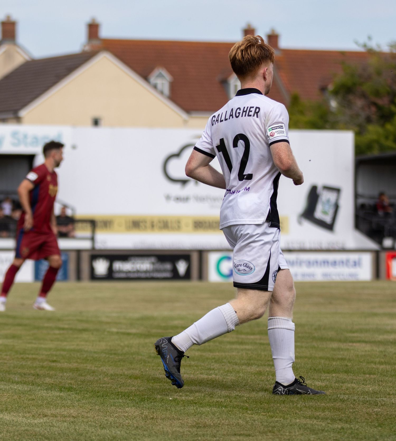 Salisbury FC player Gallagher wearing number 12 white jersey runs during a sunny football match.