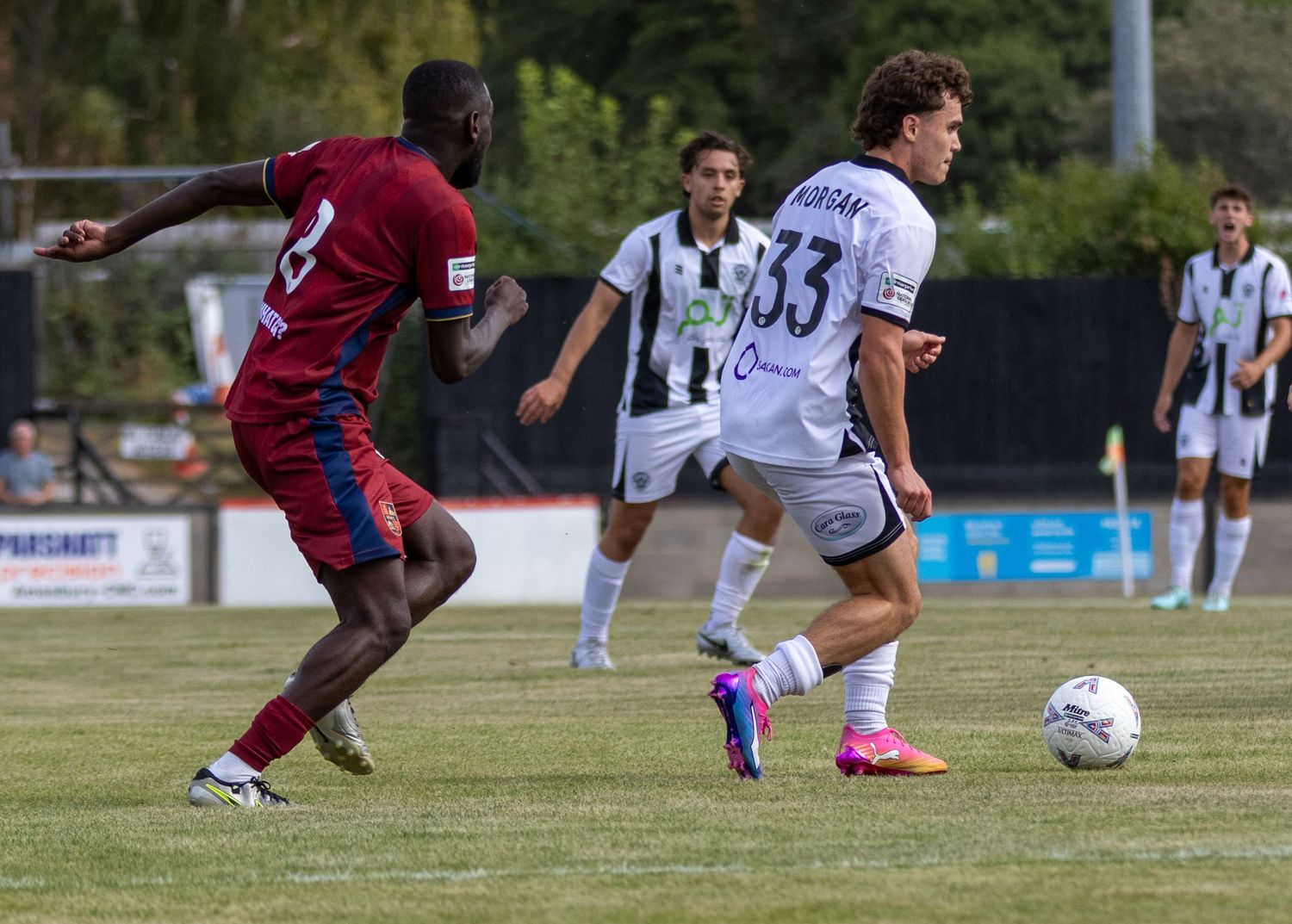 Salisbury FC player number 33 dribbles past a red-shirted defender during a non-league match.