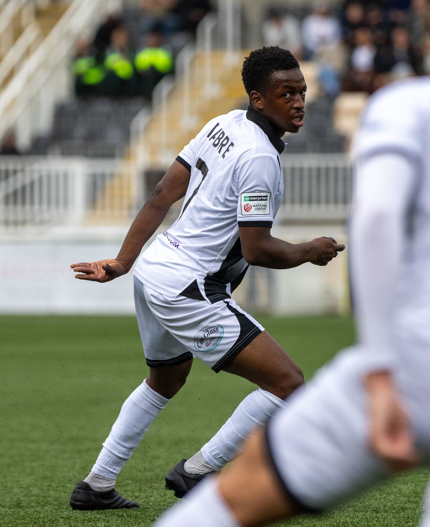 Soccer player in white uniform dribbling on the field during a competitive match.