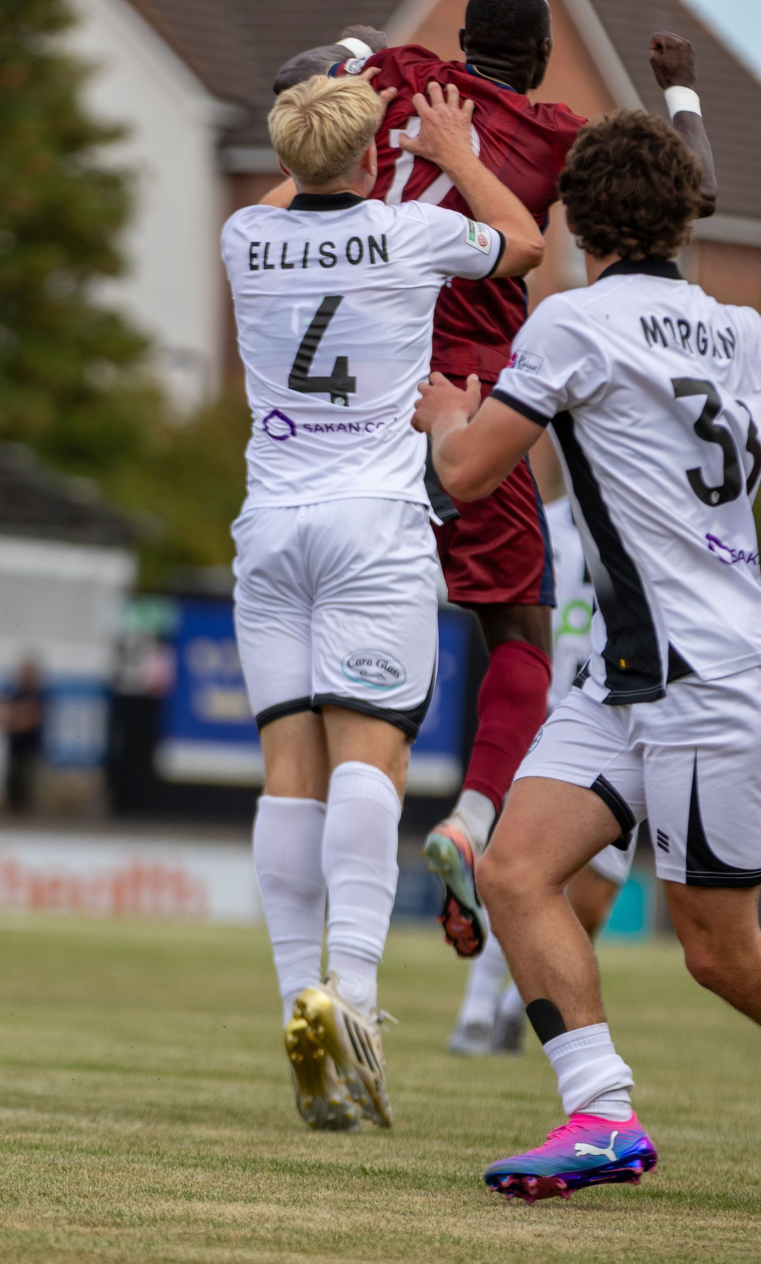 Player Ellison number 4 in white kit challenges opponent in maroon during competitive football match.