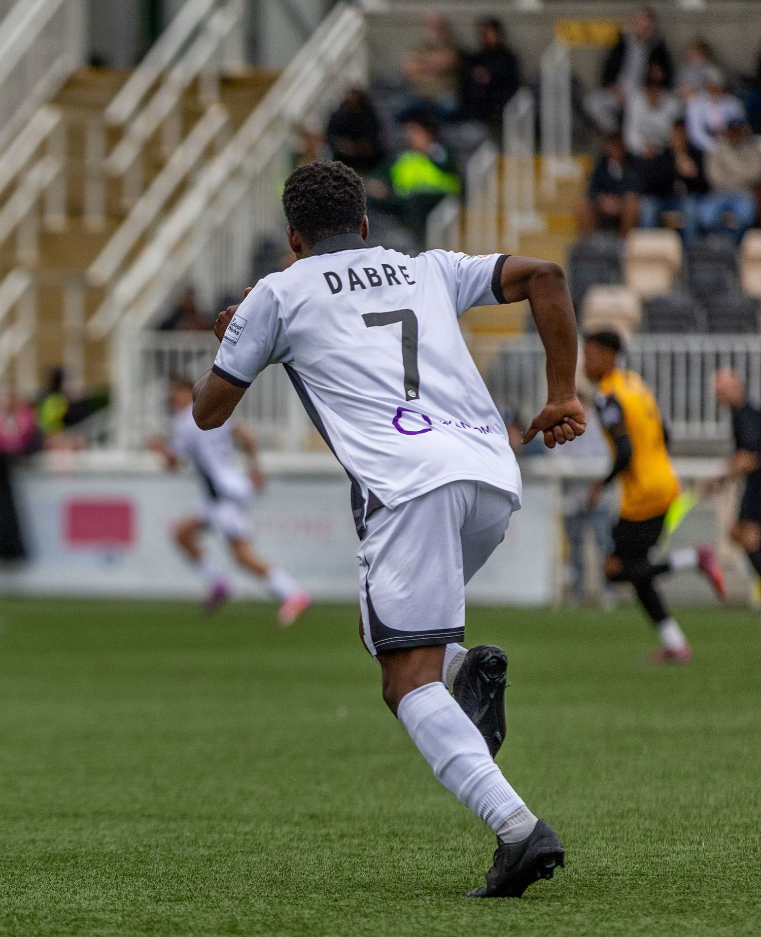 Soccer player Dabre wearing number 7 white jersey and white socks runs on the field during a match.