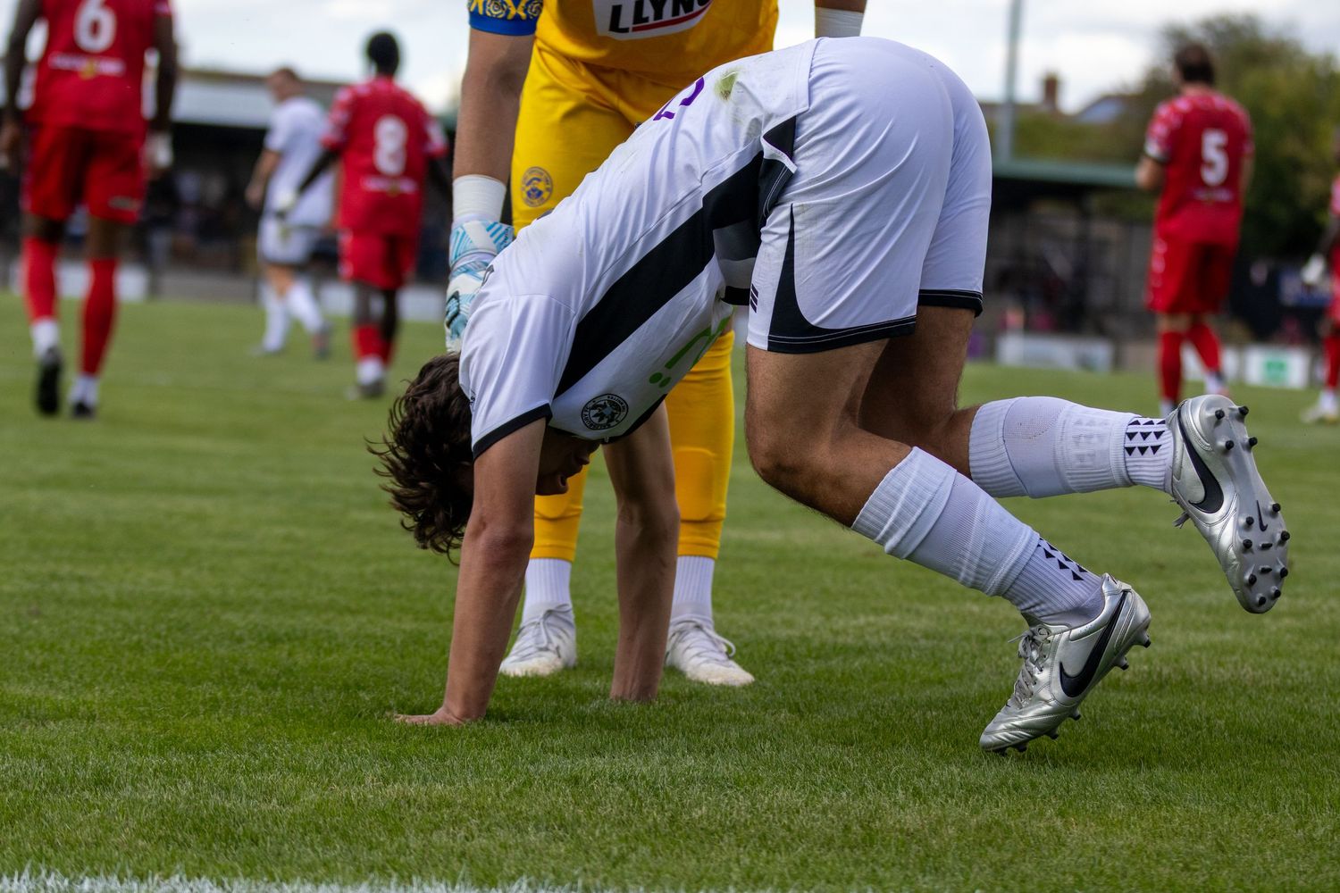 Soccer player bends down on the grass pitch during a football match.