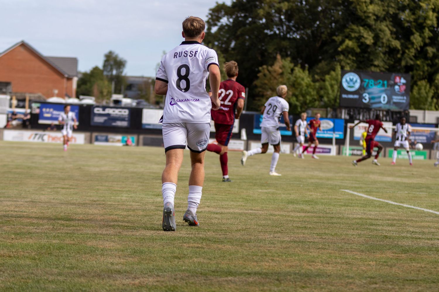 Football player number 8 MORSE in white kit walks on pitch during sunny outdoor soccer game.