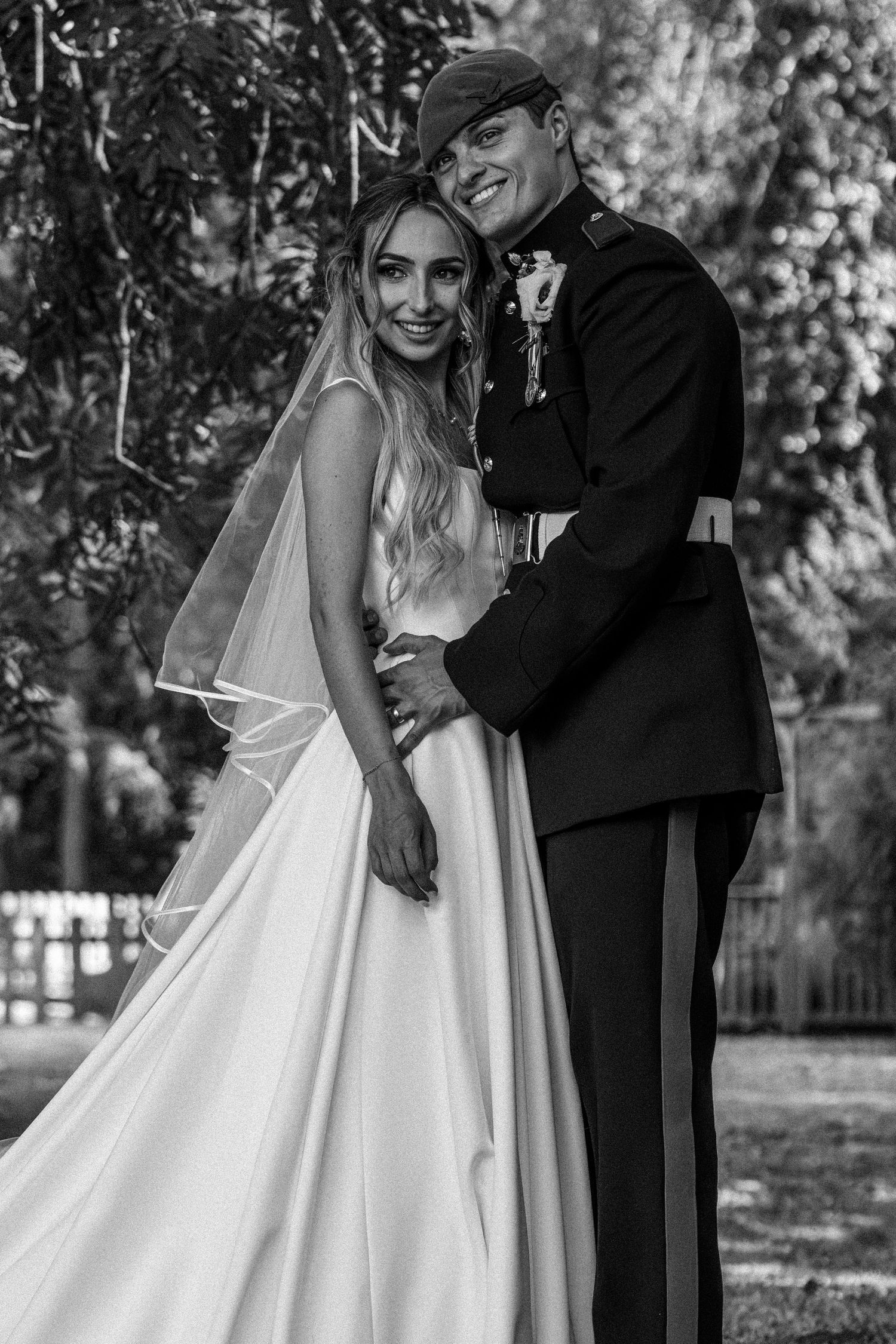 Black and white portrait of smiling bride and groom in military uniform.