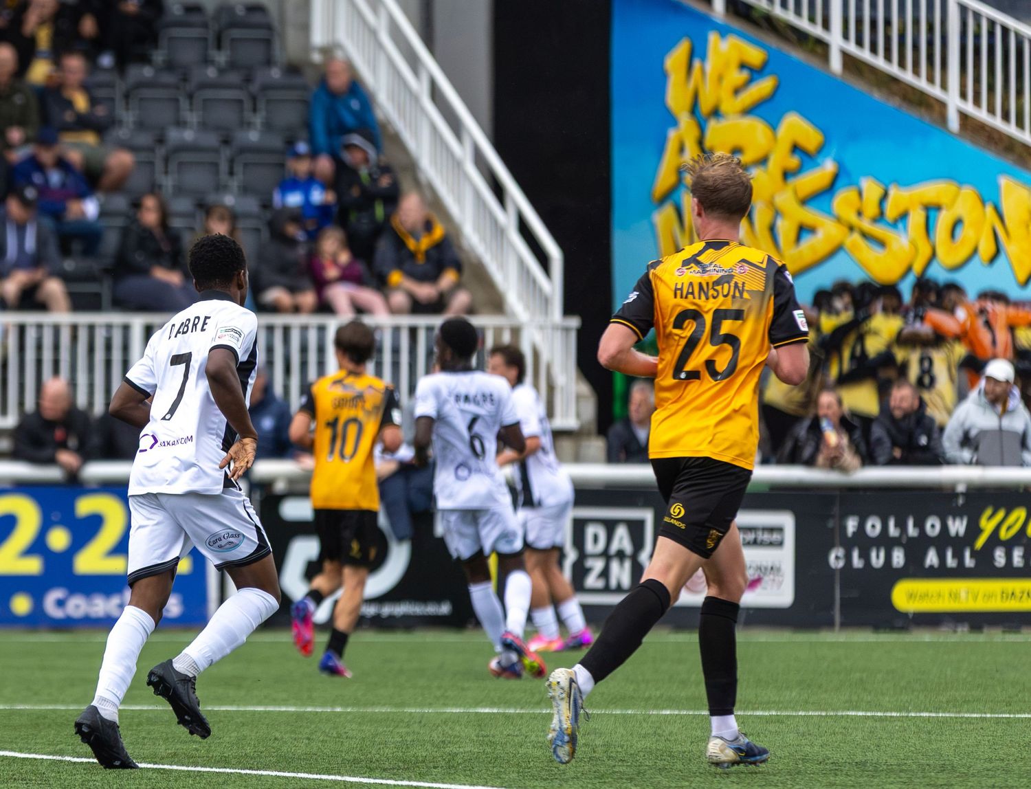 Soccer players in yellow and black uniforms compete on a professional football pitch during an intense match.