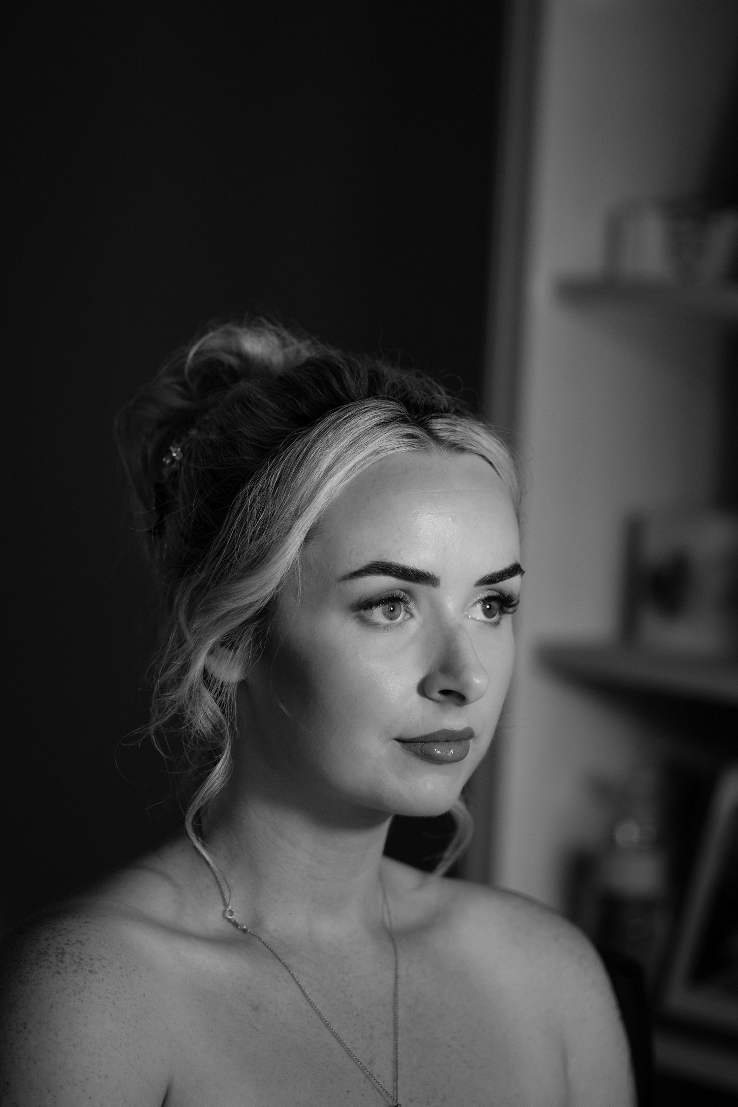 A black and white portrait of a blonde woman with an updo hairstyle and elegant necklace.