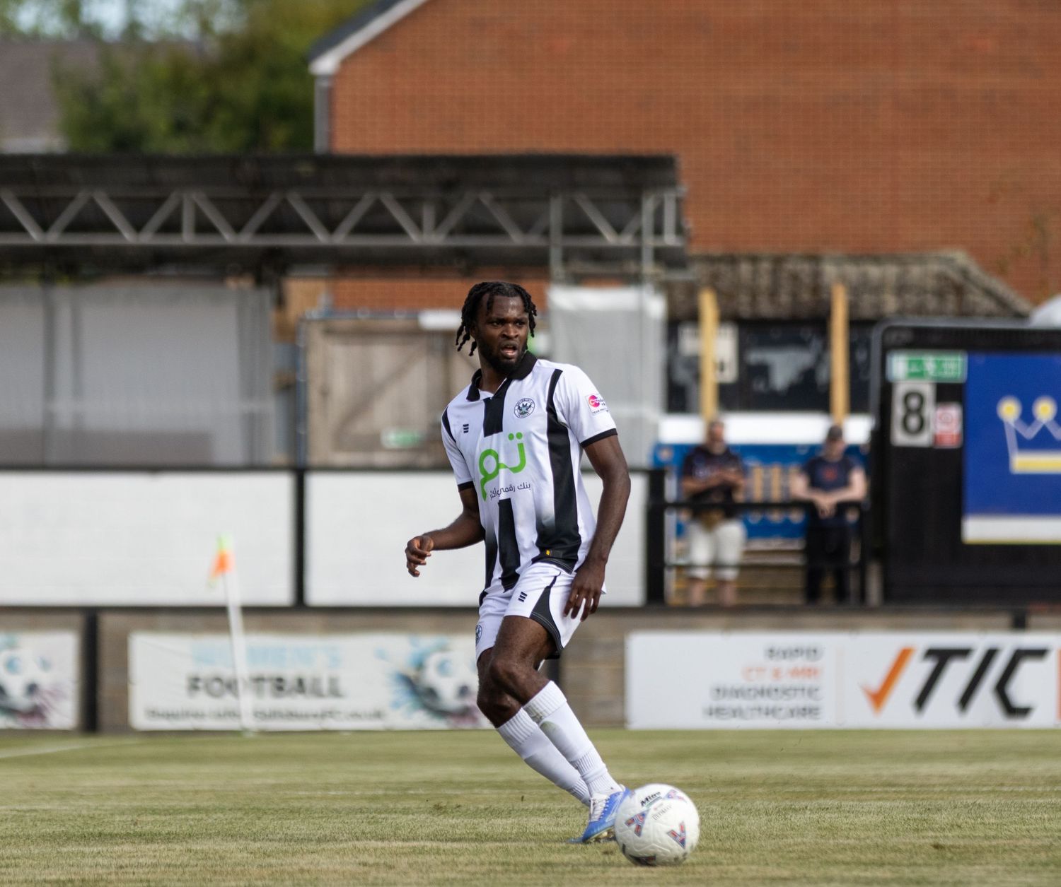 Salisbury FC player dribbles with the ball in black and white kit during a summer fixture.