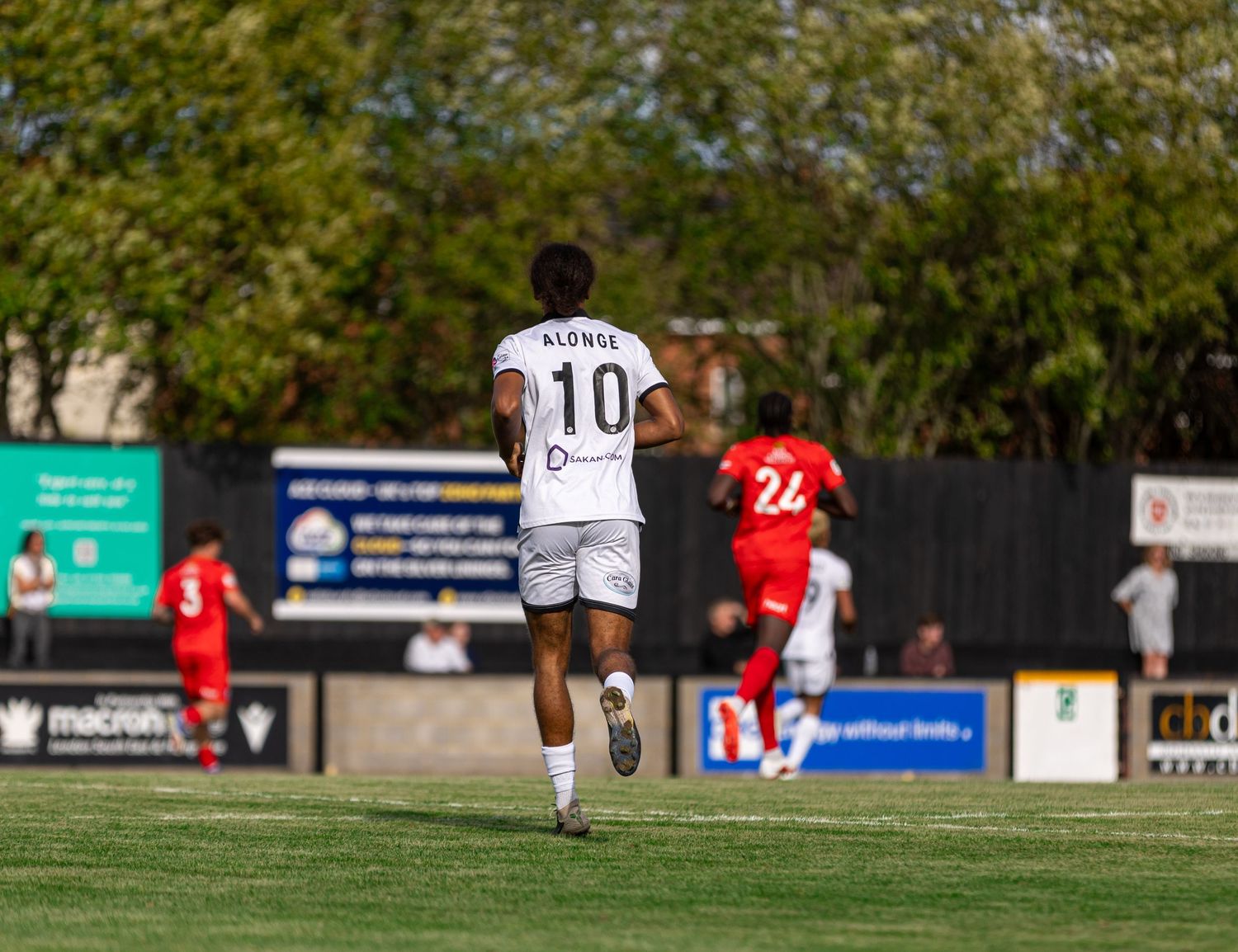 Soccer player wearing number 10 Alonso jersey runs on green field during a competitive match on a sunny day.
