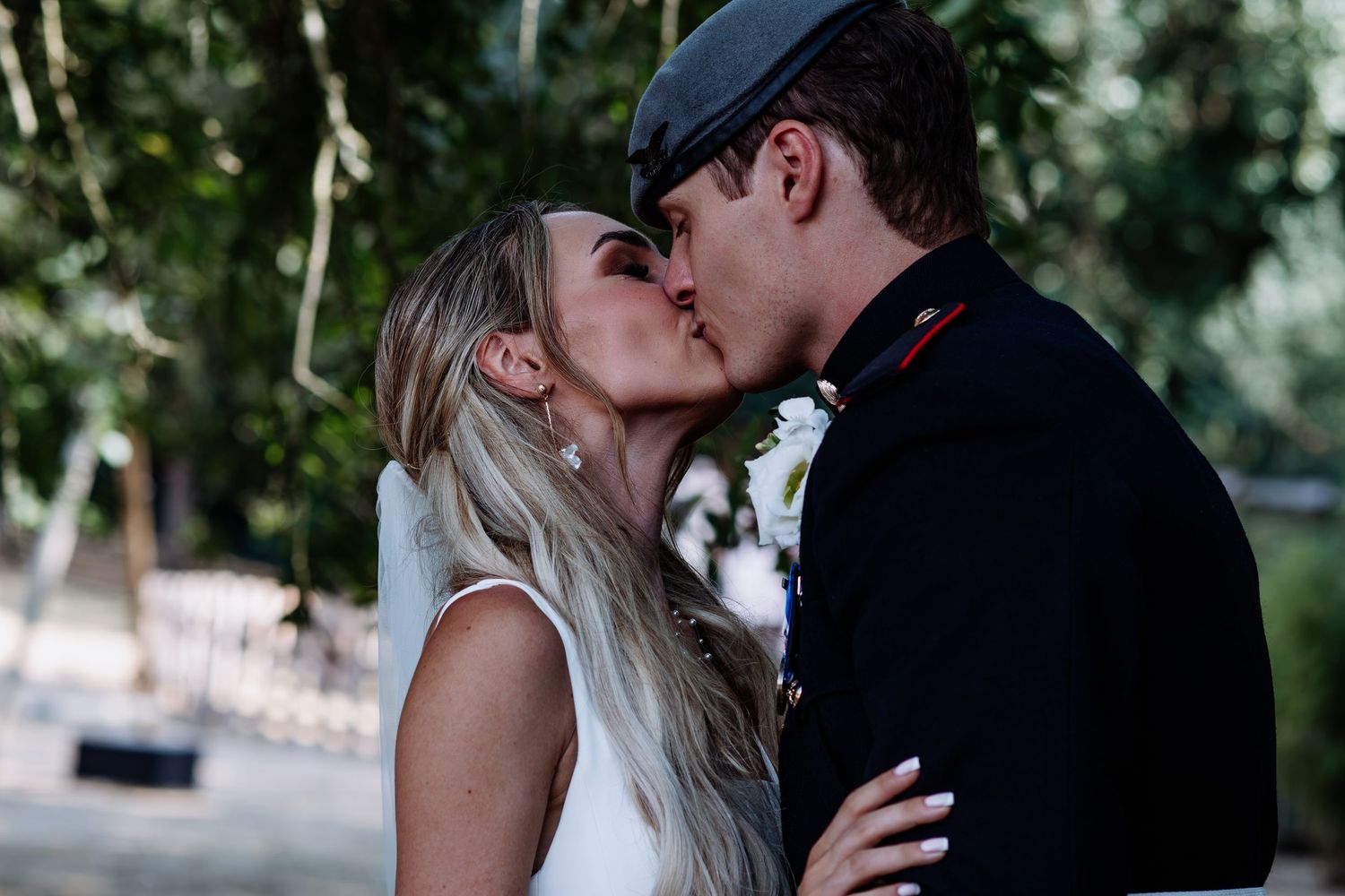 Bride and groom share a romantic kiss outdoors on their wedding day.