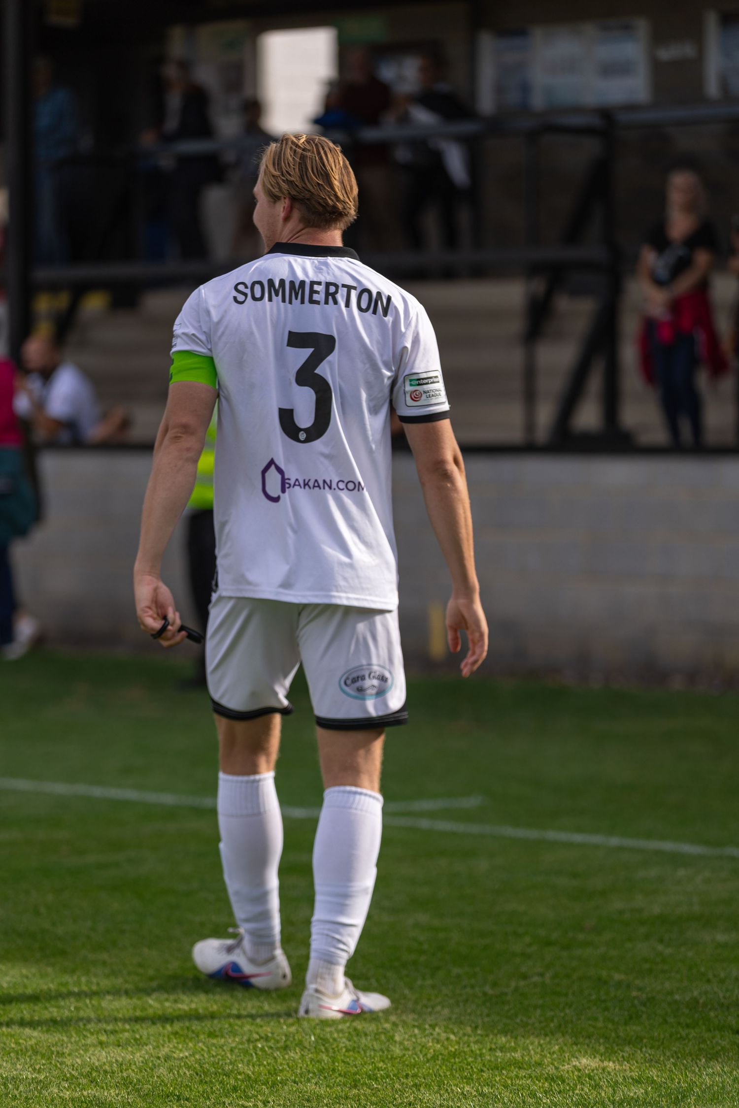 Soccer player Sommerton wearing number 3 white jersey walks on green pitch during a football match.