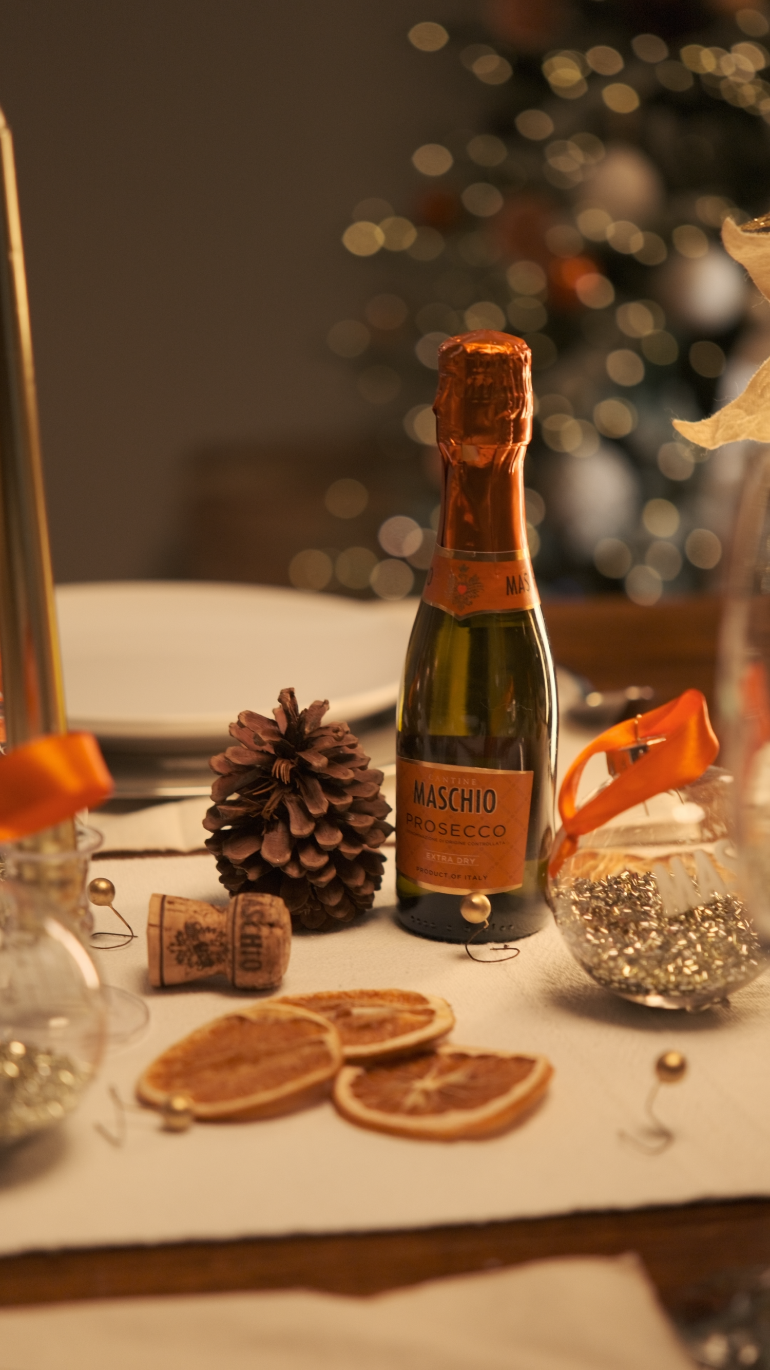 Mini Maschio Prosecco bottle on elegant Christmas table with pine cone, dried orange slices, and festive decorations.
