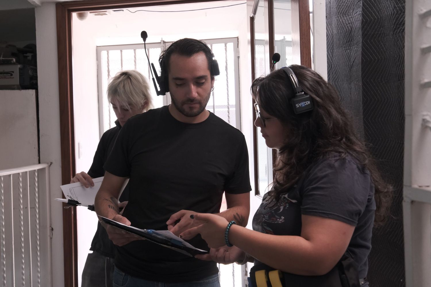 Two film crew members reviewing a script on a clipboard during a movie production.