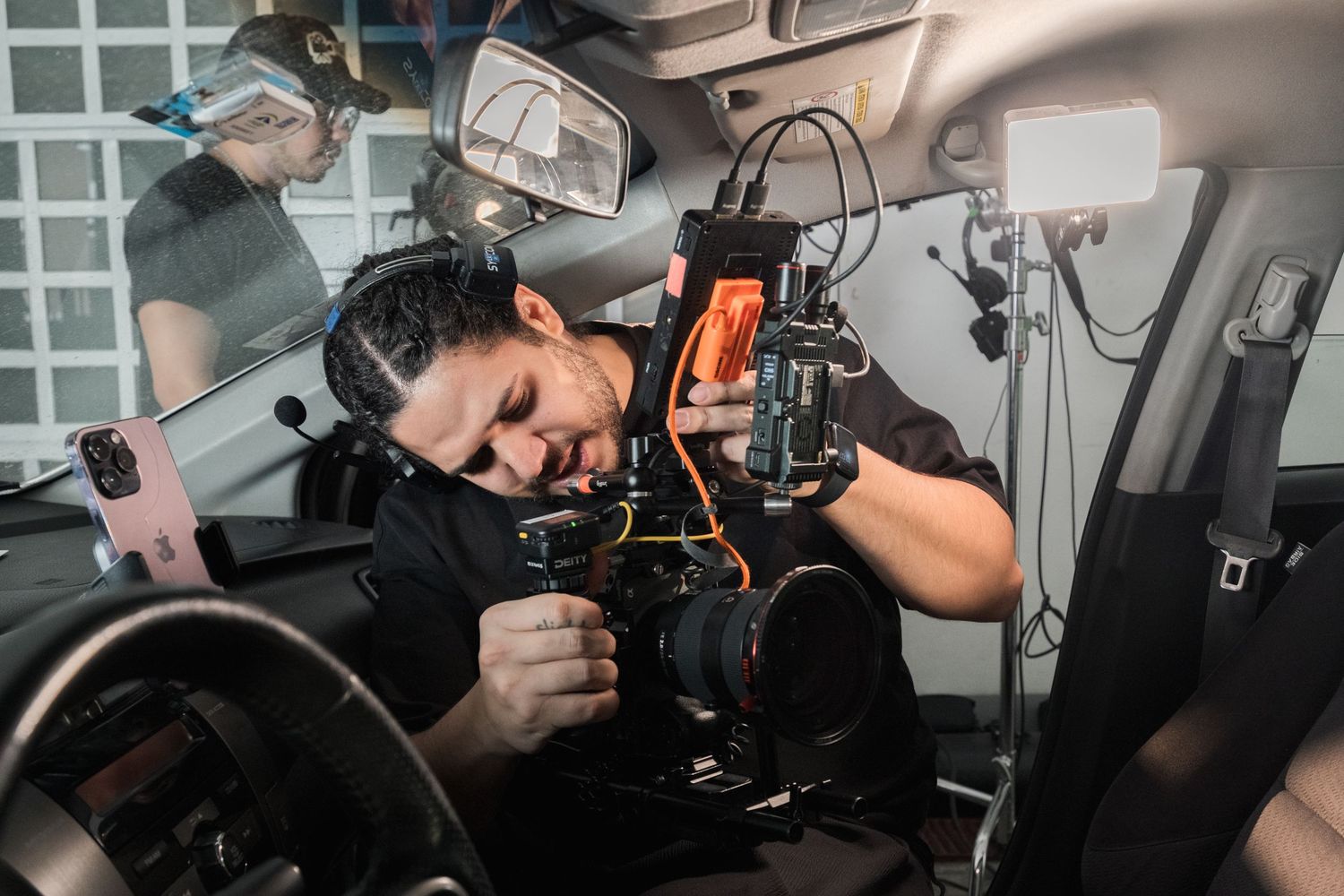 Cameraman operating a professional camera inside a vehicle on a film production set.