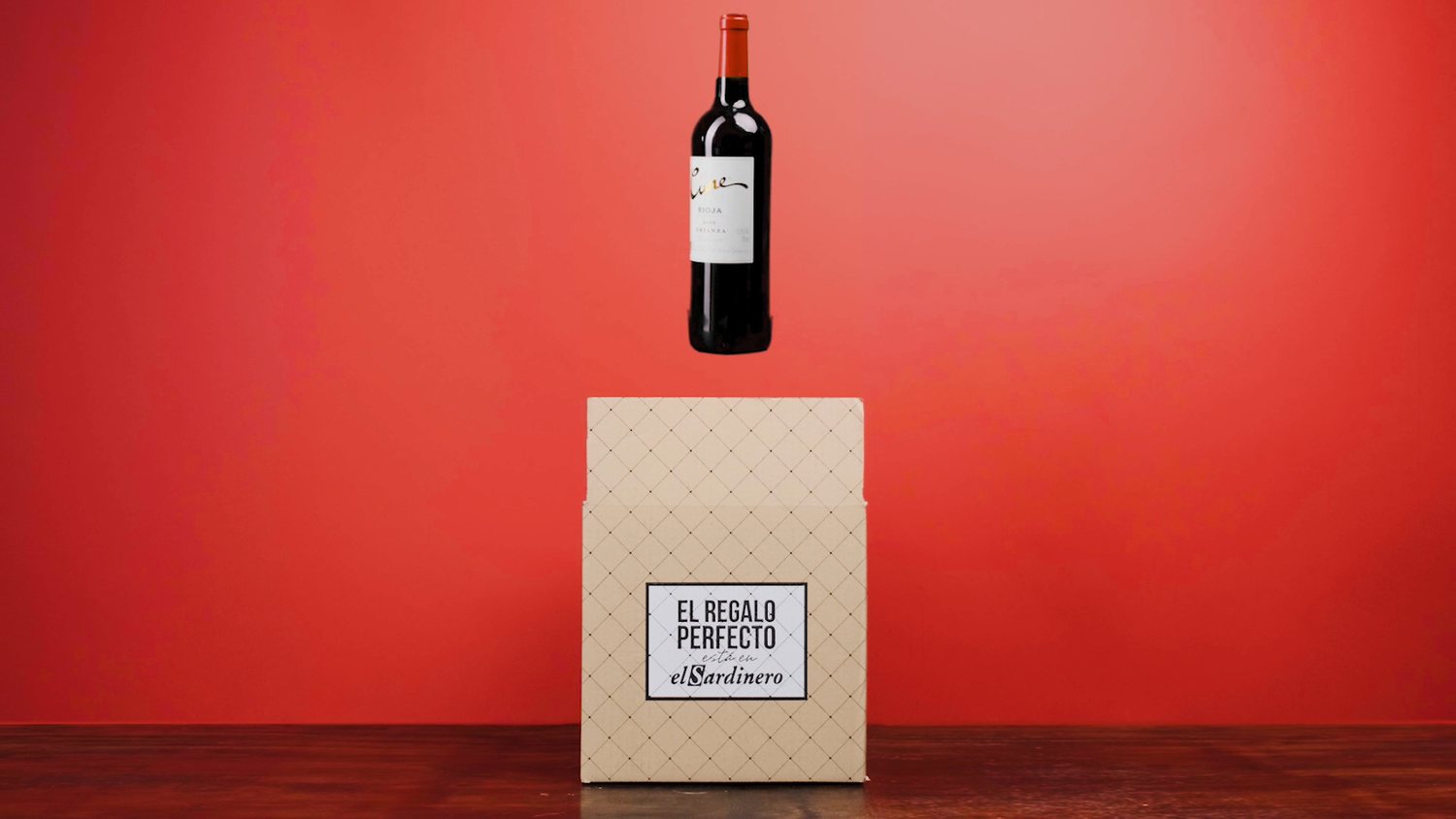 Cune red wine bottle floating above an El Sardinero gift box on a bold red background.