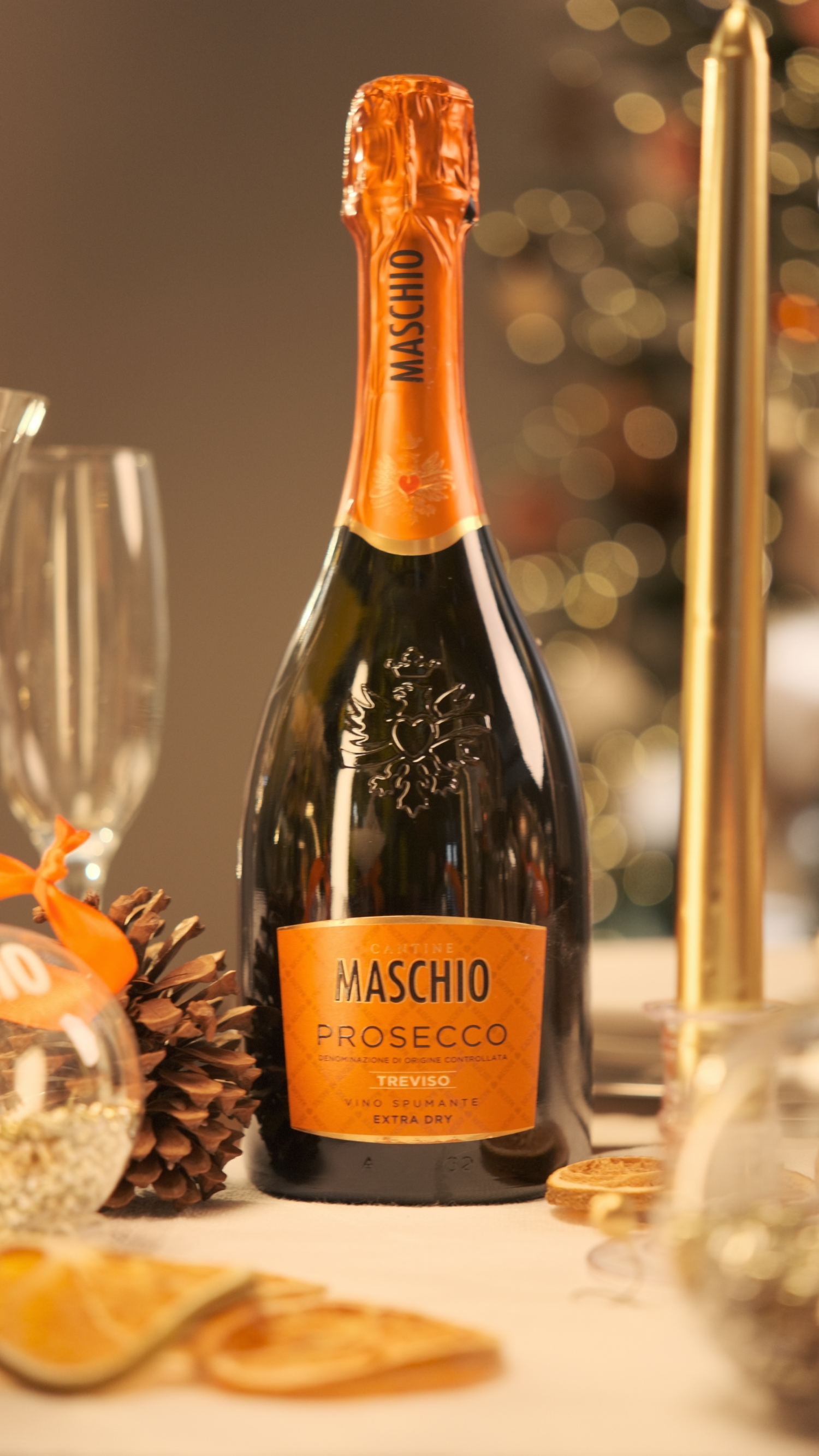 Maschio Prosecco Treviso Extra Dry bottle on elegant holiday table with pine cone and gold candlestick.