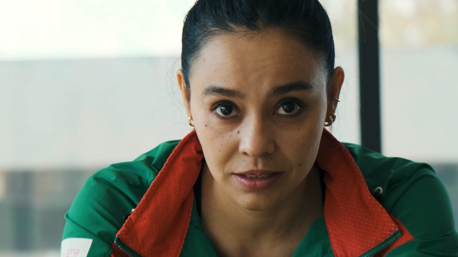 Close-up portrait of a focused female athlete in a green and red Mexico sports jacket.