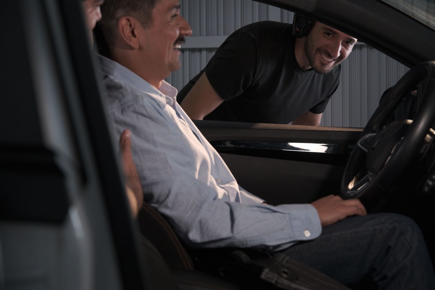 Two men sharing a conversation inside a car during a nighttime film production shoot.