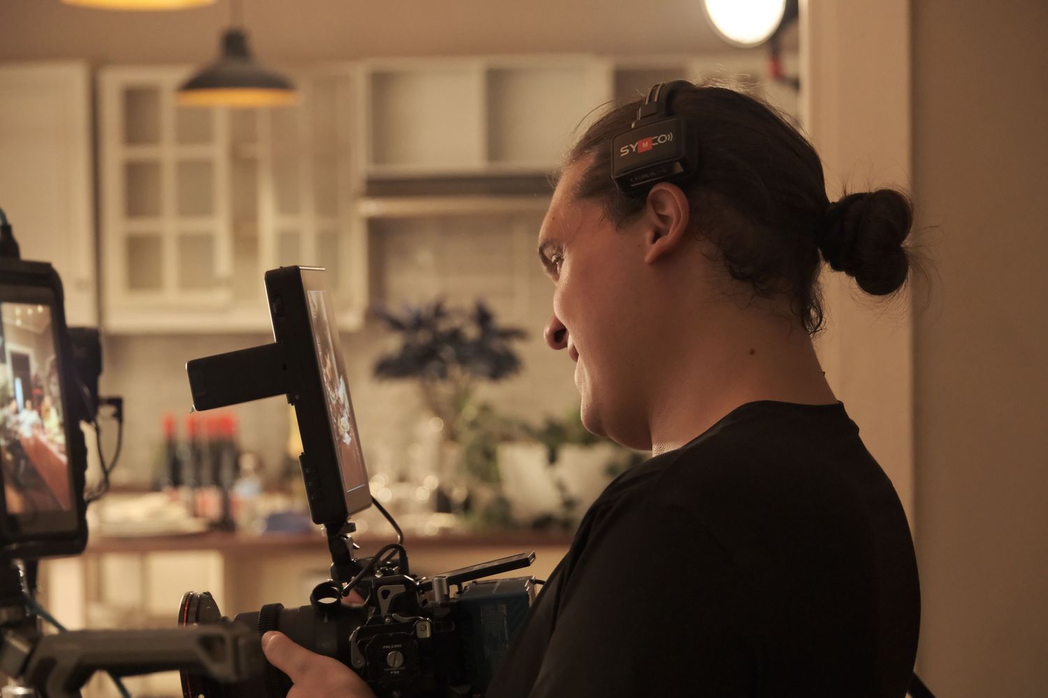 Female camera operator monitoring footage on a professional camera rig during an indoor film production.
