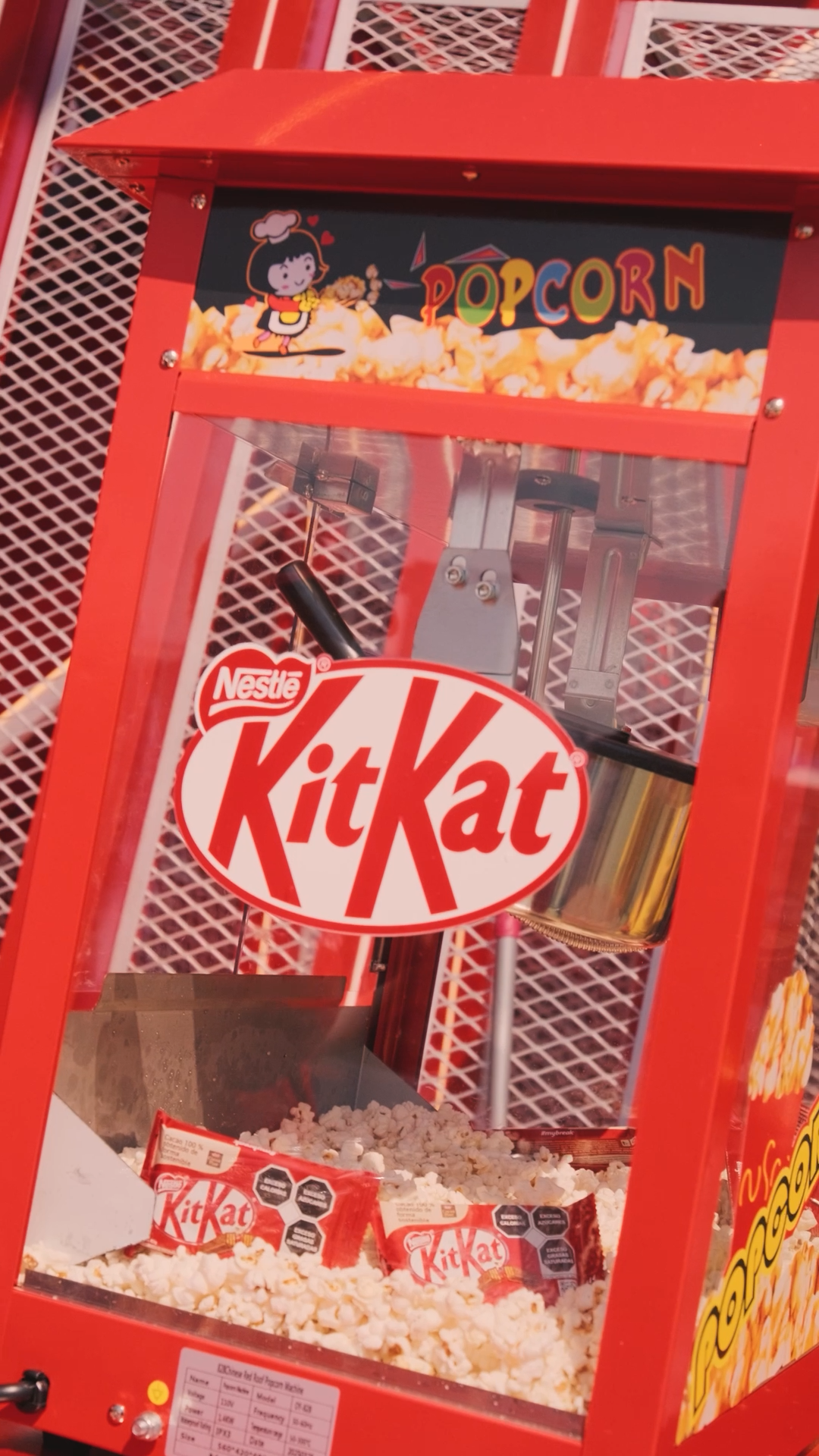 KitKat branded popcorn machine filled with fresh popcorn and KitKat chocolate bars at a promotional event.