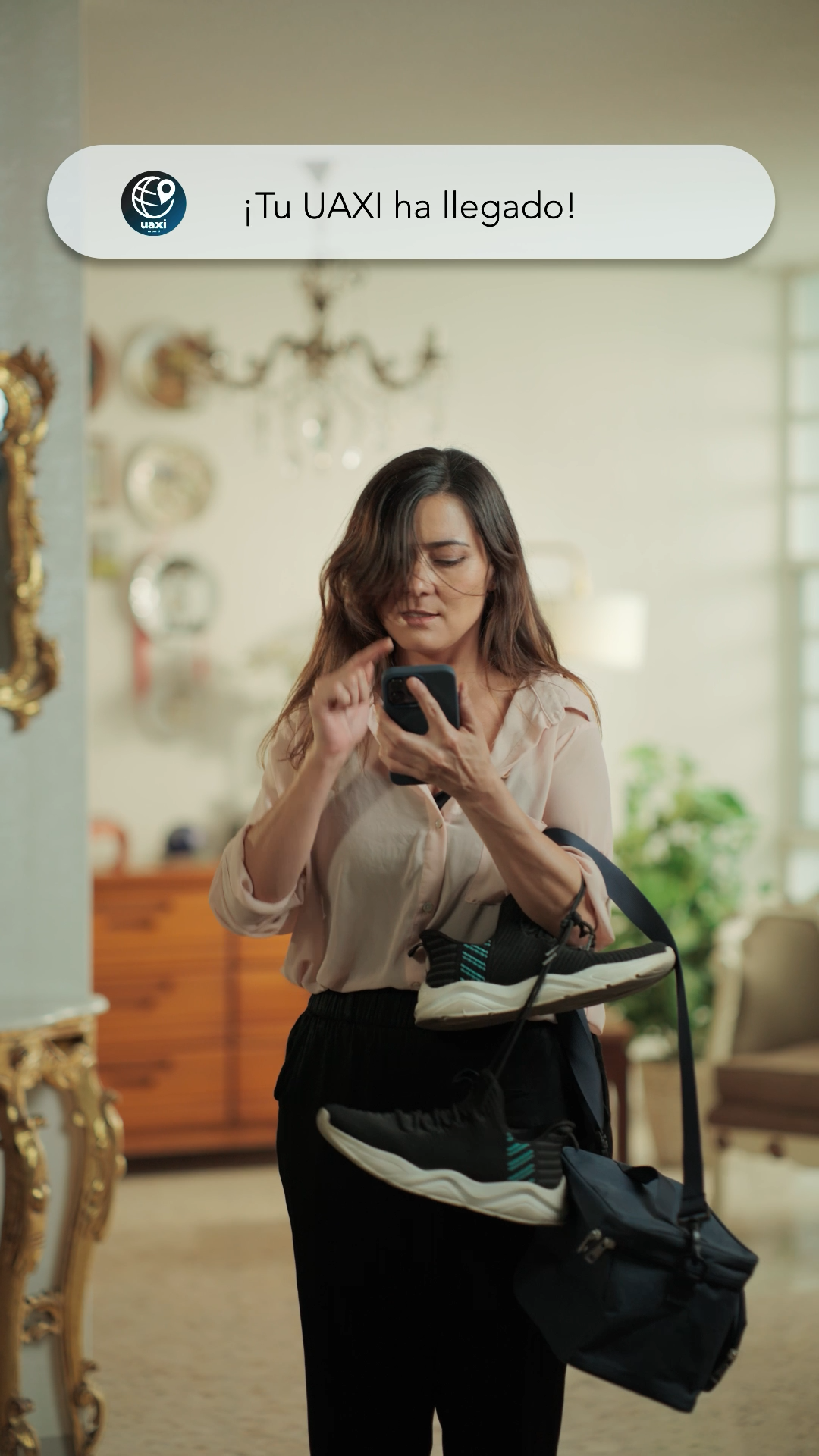 Woman with gym bag receiving Tu UAXI ha llegado notification on smartphone at home.