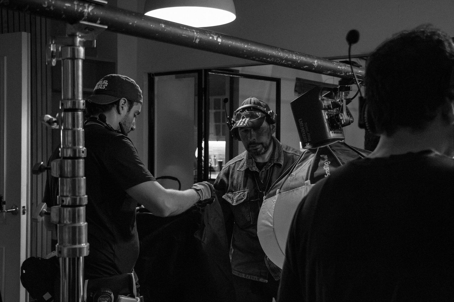 Film crew members collaborate near industrial pipe equipment during a professional video production.