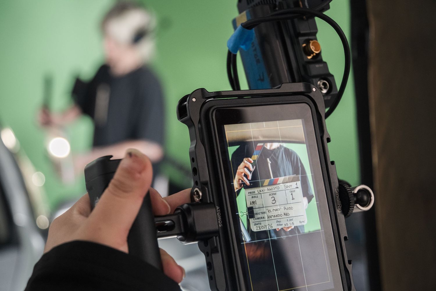 A camera operator films a scene through a monitor displaying a clapperboard on a film set.