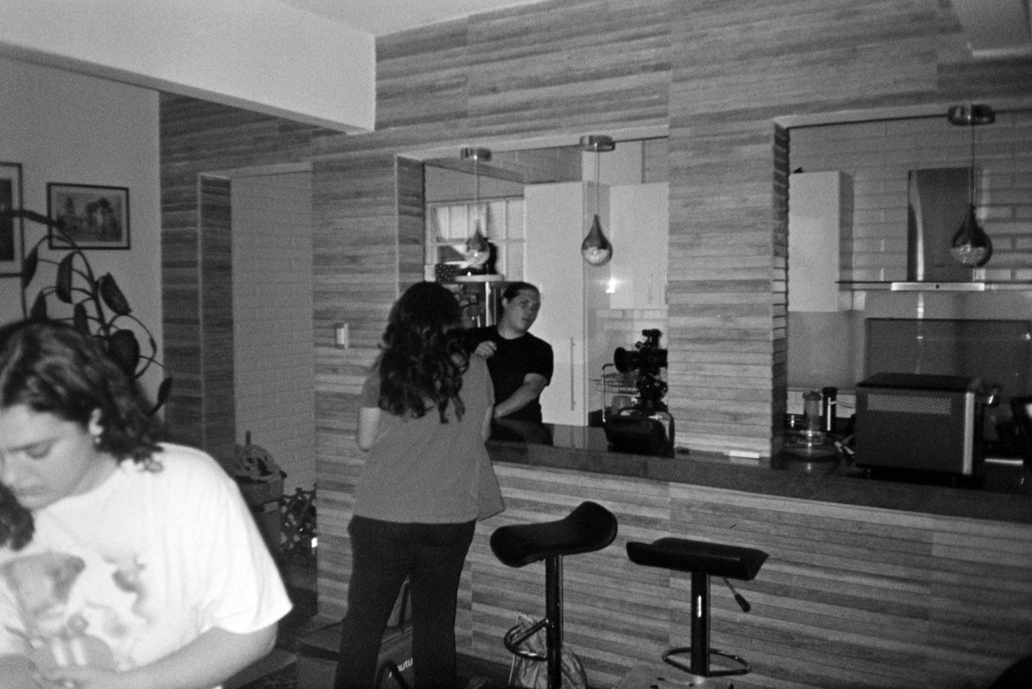 Film crew members work inside a modern bar setting during an indoor video production shoot.
