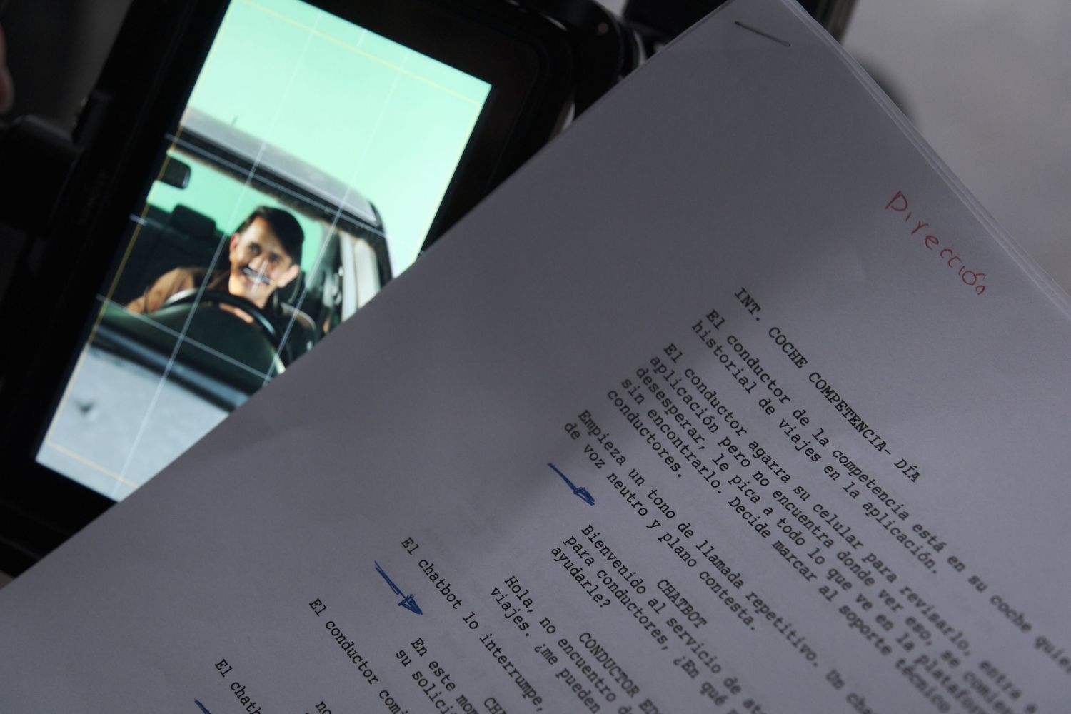 Behind-the-scenes film production script visible in foreground with actor seated in vehicle background.