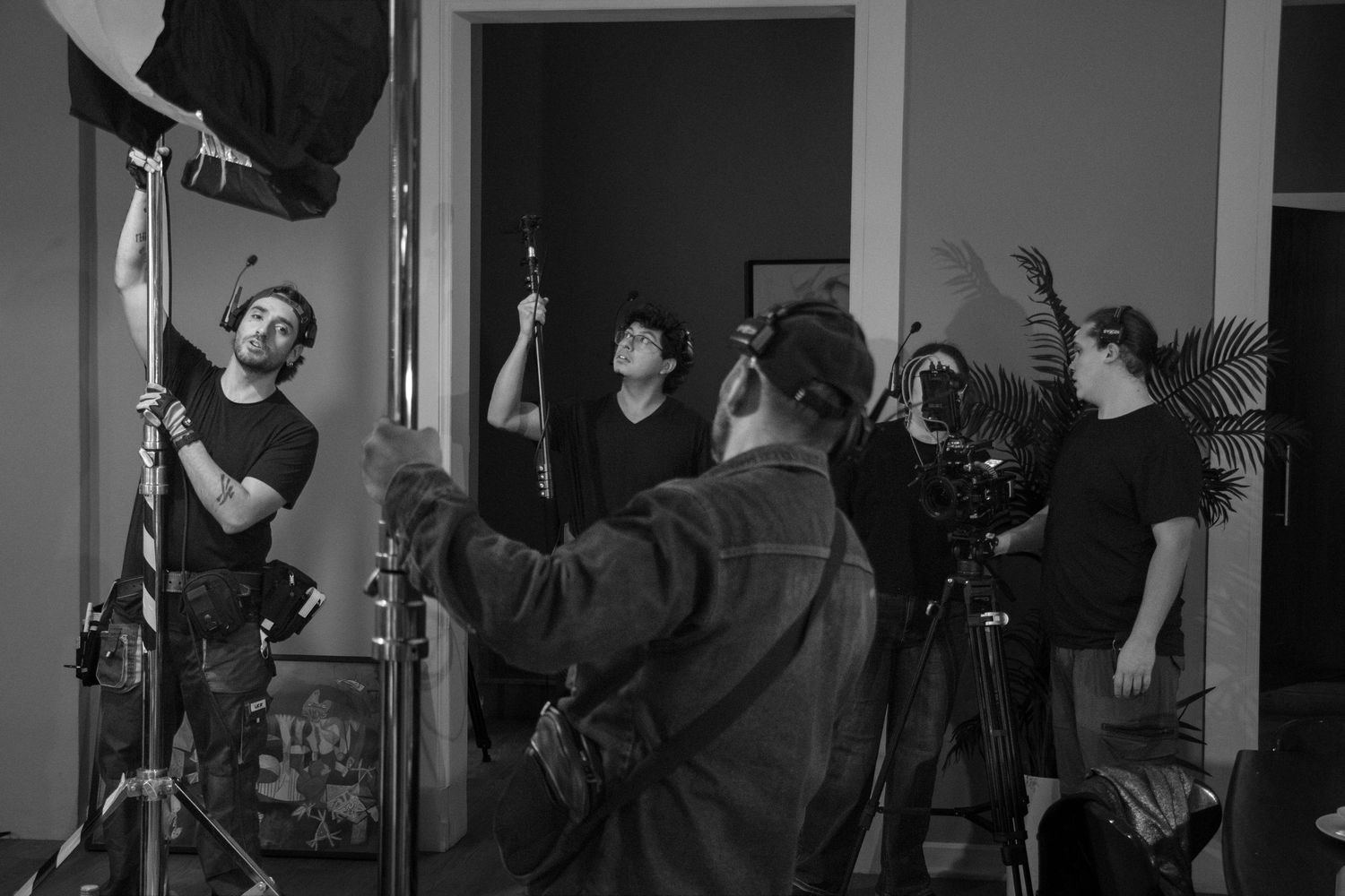 Black and white behind-the-scenes photo of film crew adjusting lighting equipment on a movie set.
