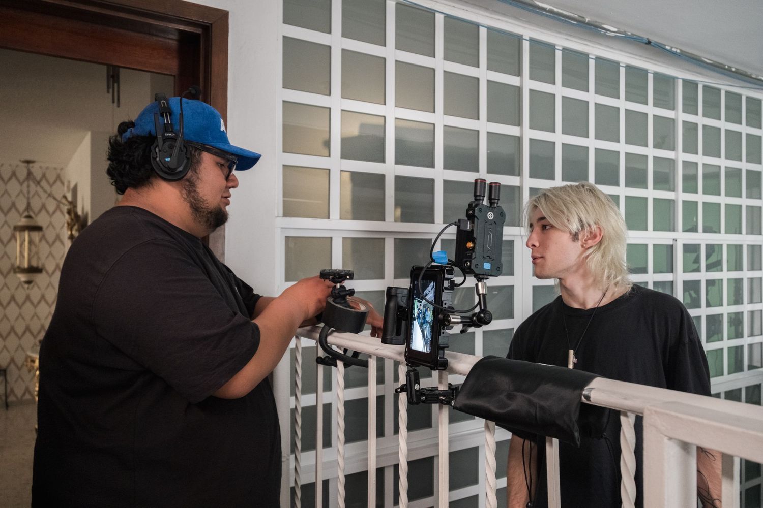 Two film crew members reviewing camera equipment on a balcony during production.