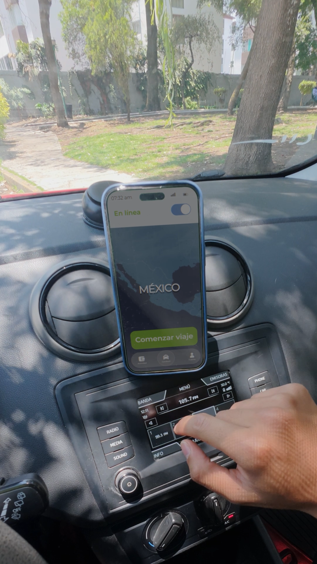 Smartphone mounted on car dashboard showing Mexico travel app with Comenzar viaje button.