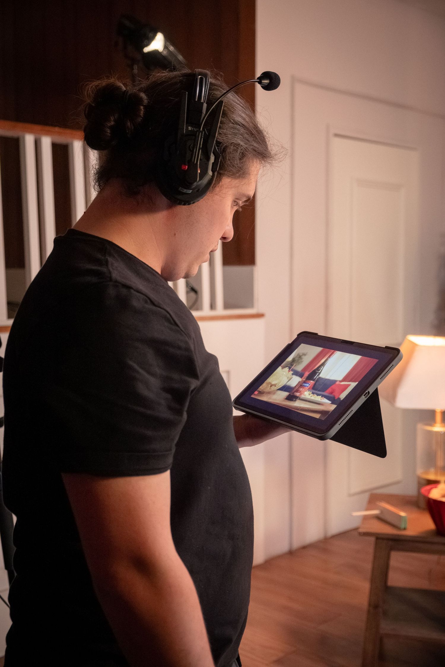 Person wearing headphones reviews footage on a tablet during a video production shoot indoors.