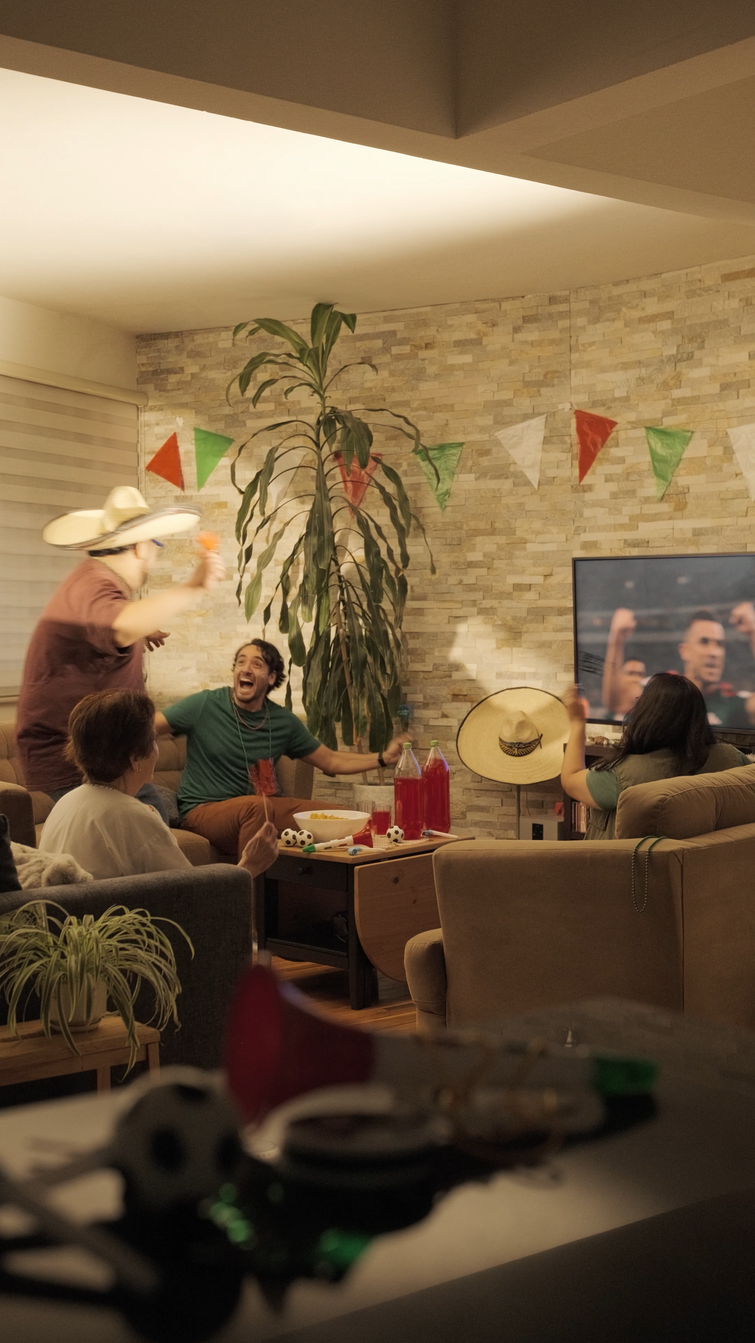 Group of friends celebrating with Mexican decorations watching sports on TV indoors.