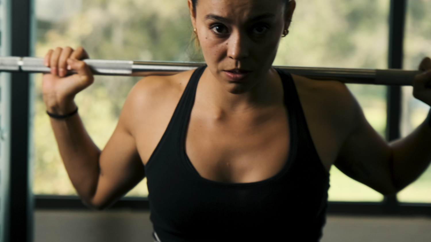 A determined woman lifts a barbell during an intense weightlifting workout at the gym.