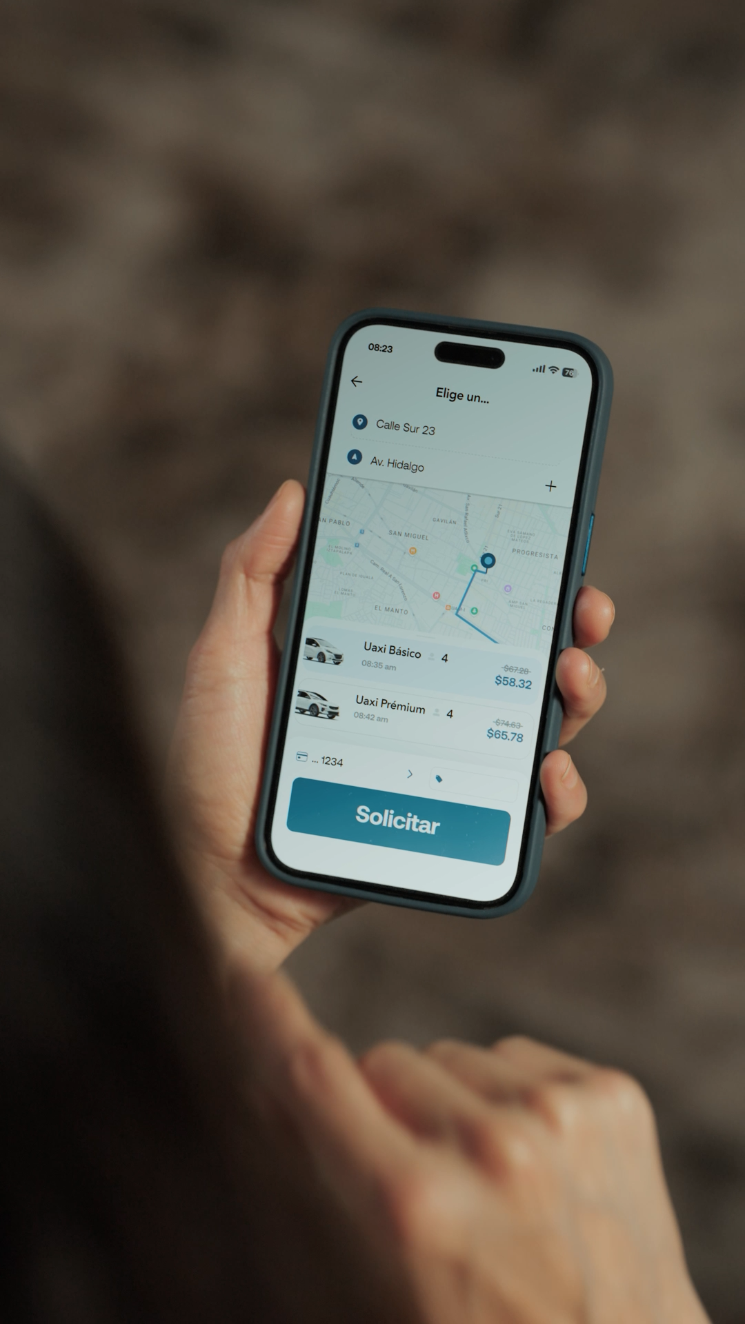 Hand holding iPhone displaying Uber app map with ride options and Solicitar button.
