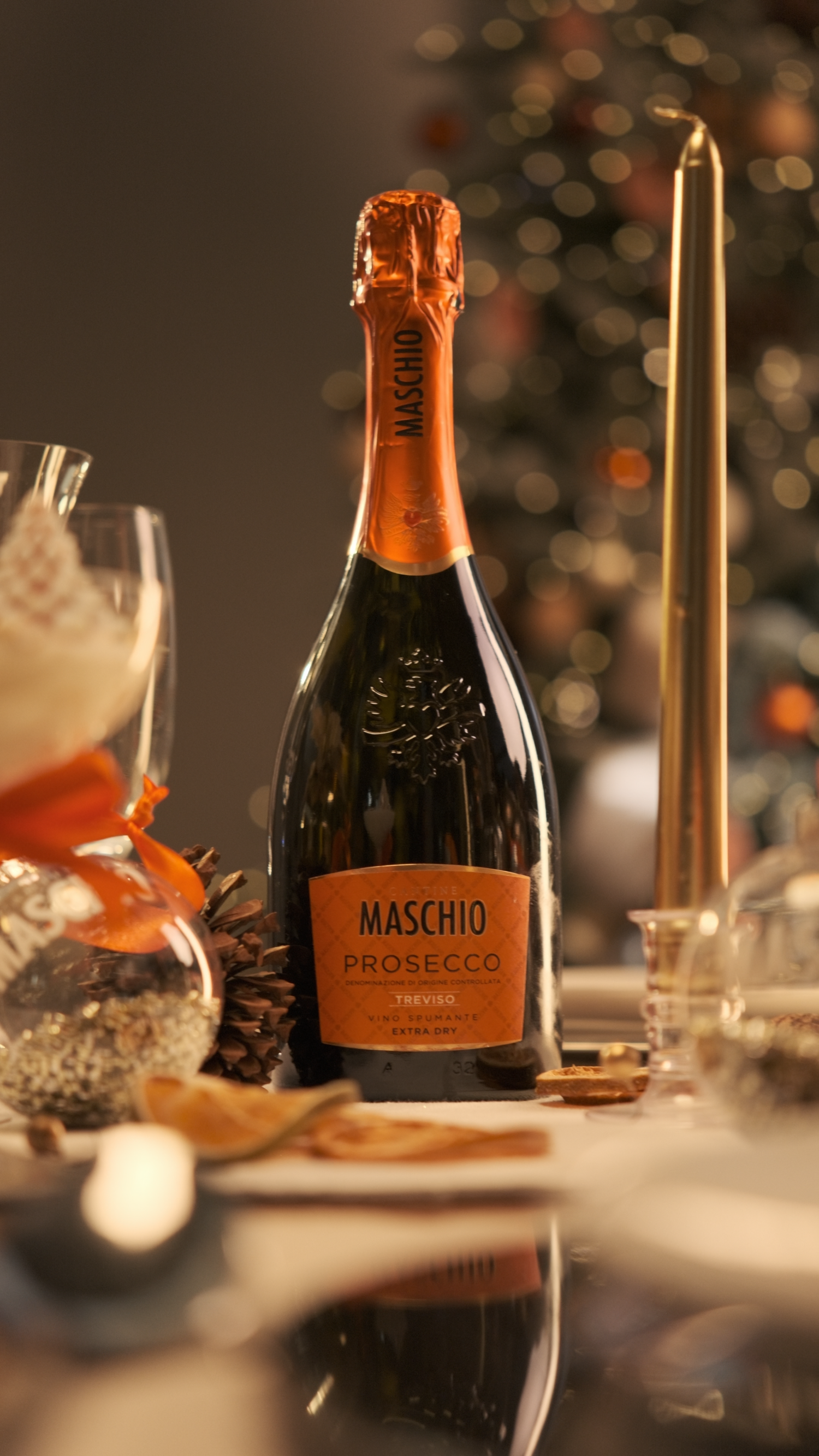 Maschio Prosecco Treviso Extra Dry bottle on decorated holiday table with pine cone and gold candle.